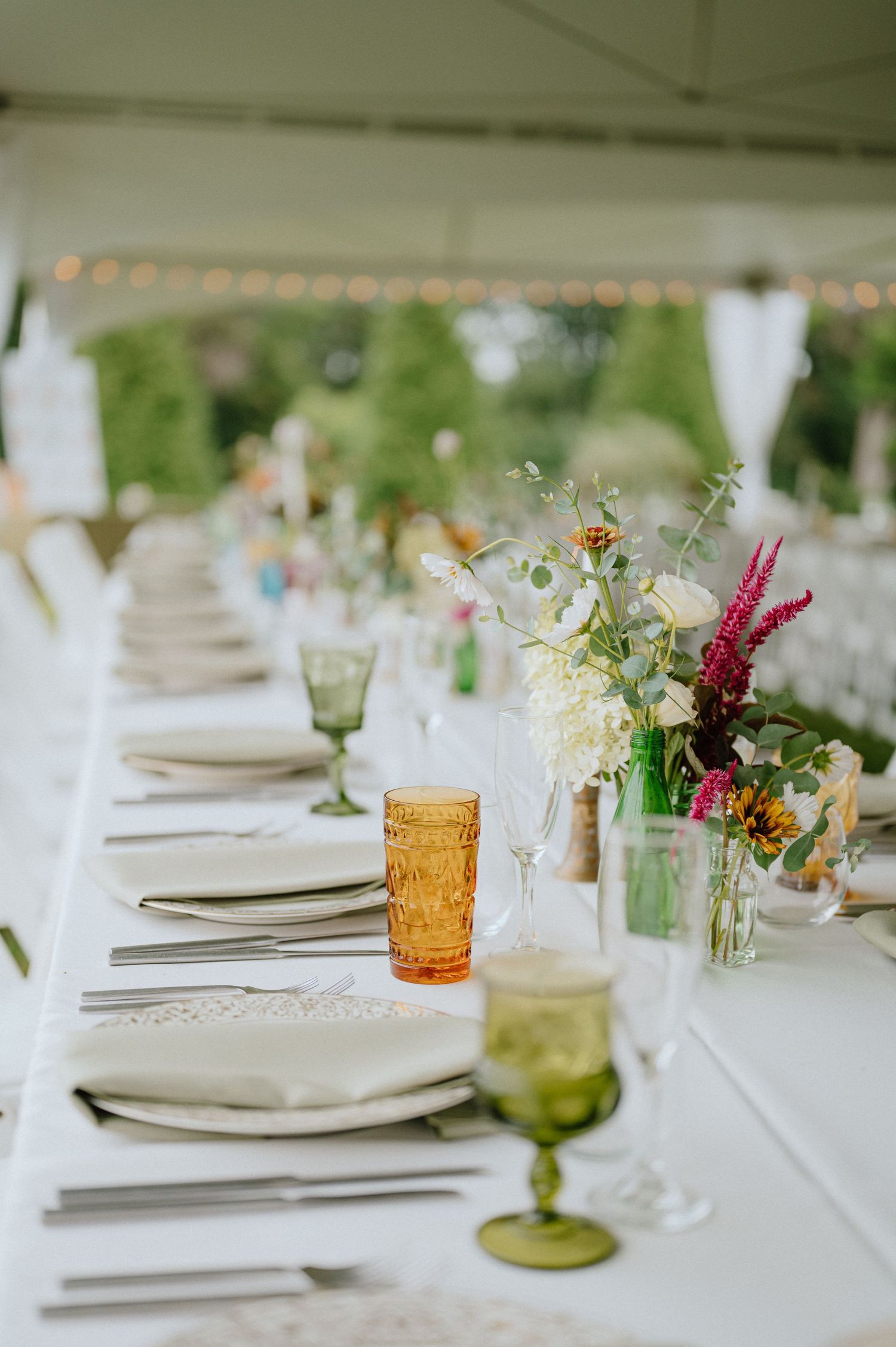 A beautifully set wedding table with colorful glassware and delicate wildflower arrangements.