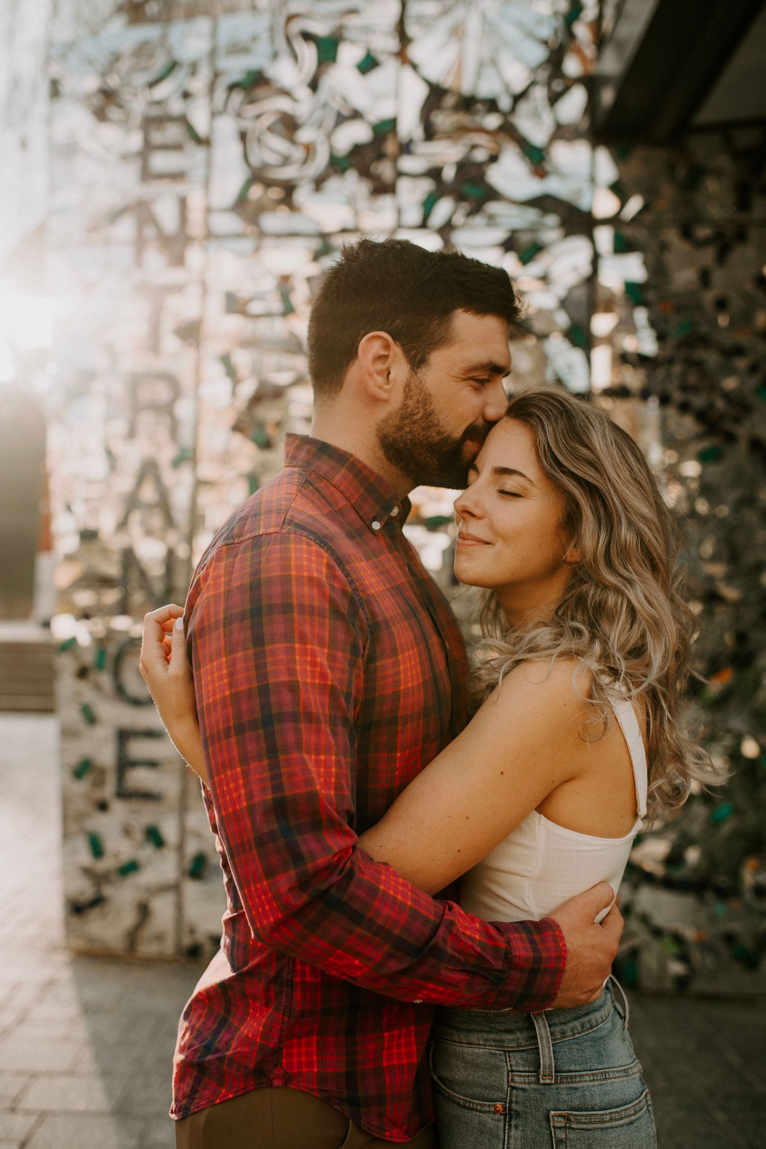 Intimate couple embrace against graffiti wall in urban setting.