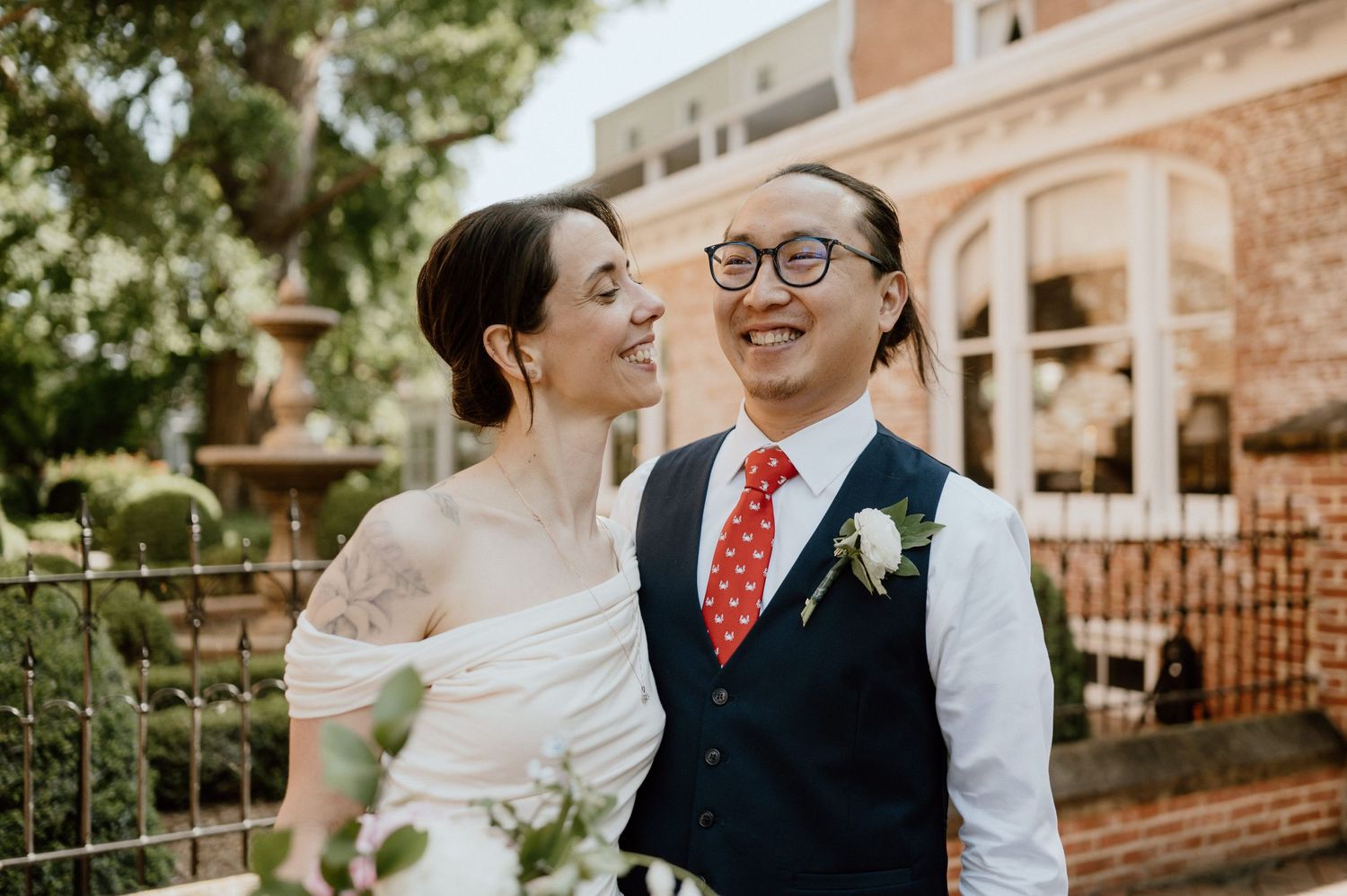 A newly married couple shares an intimate candid moment in front of historic architecture.