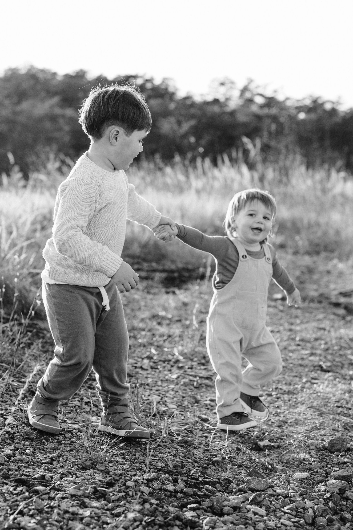 Two children share a playful moment together in black and white.