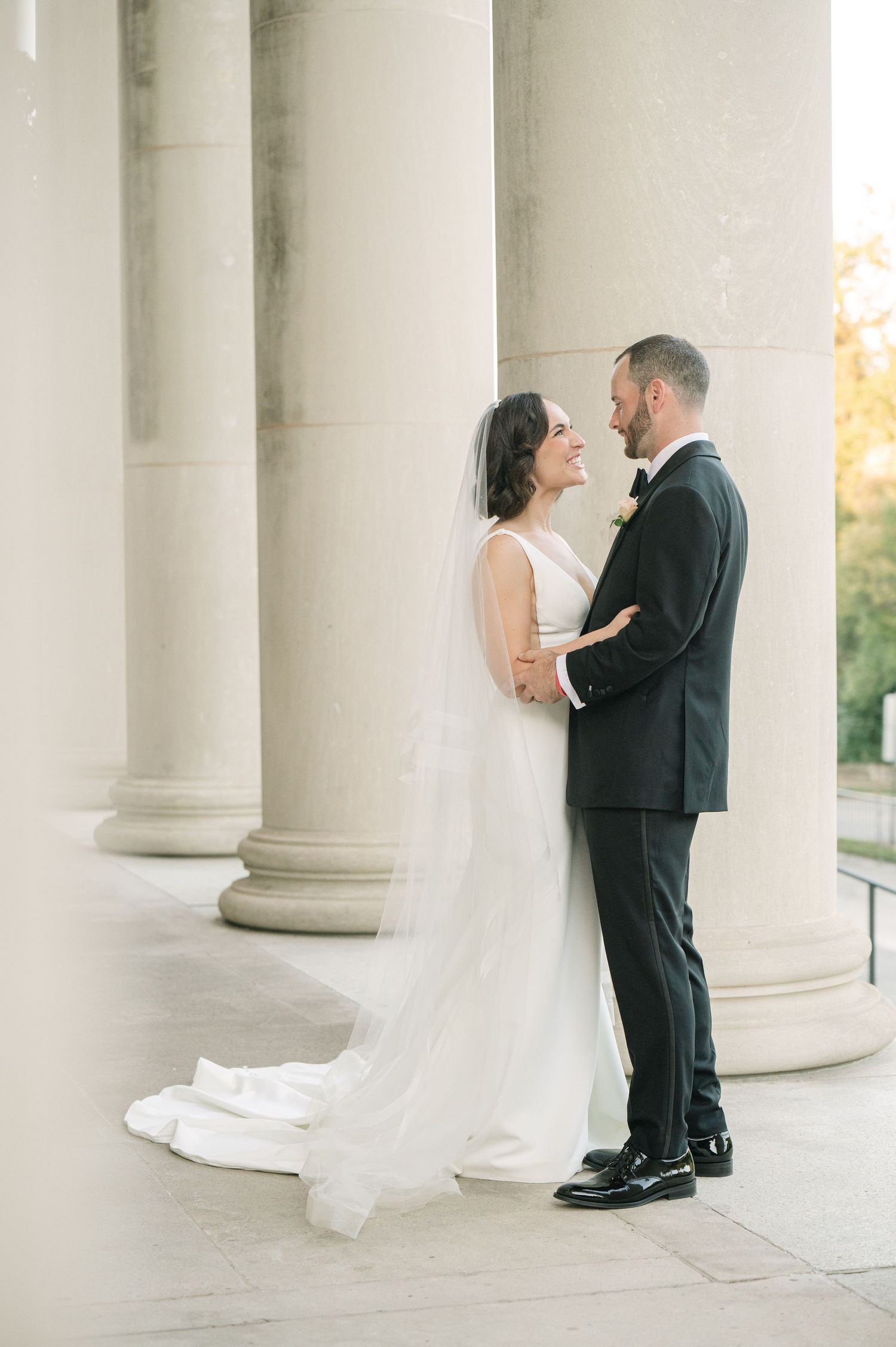 Romantic moment between couple among grand white columns.