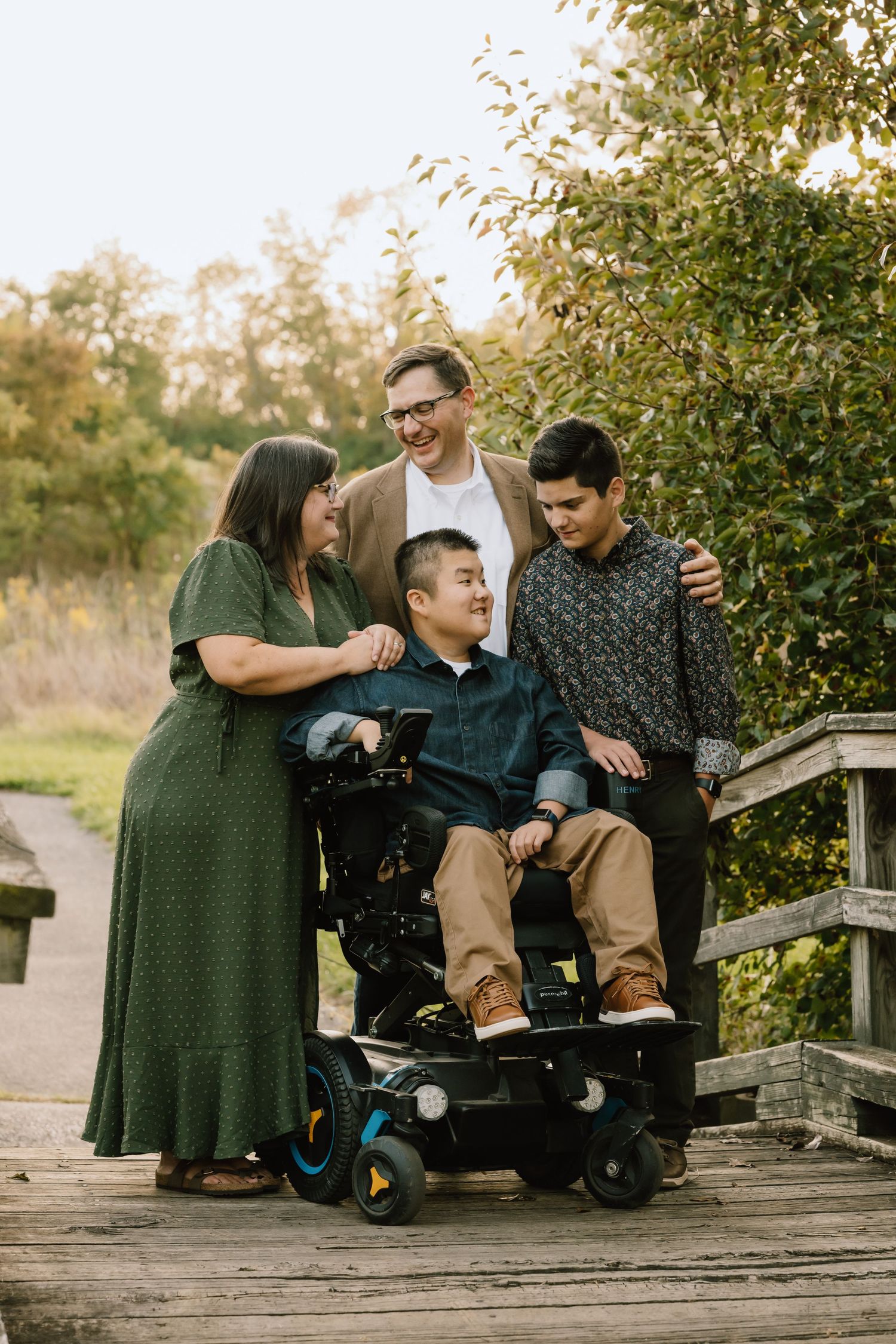 Family gathered together on wooden bridge surrounded by autumn foliage.