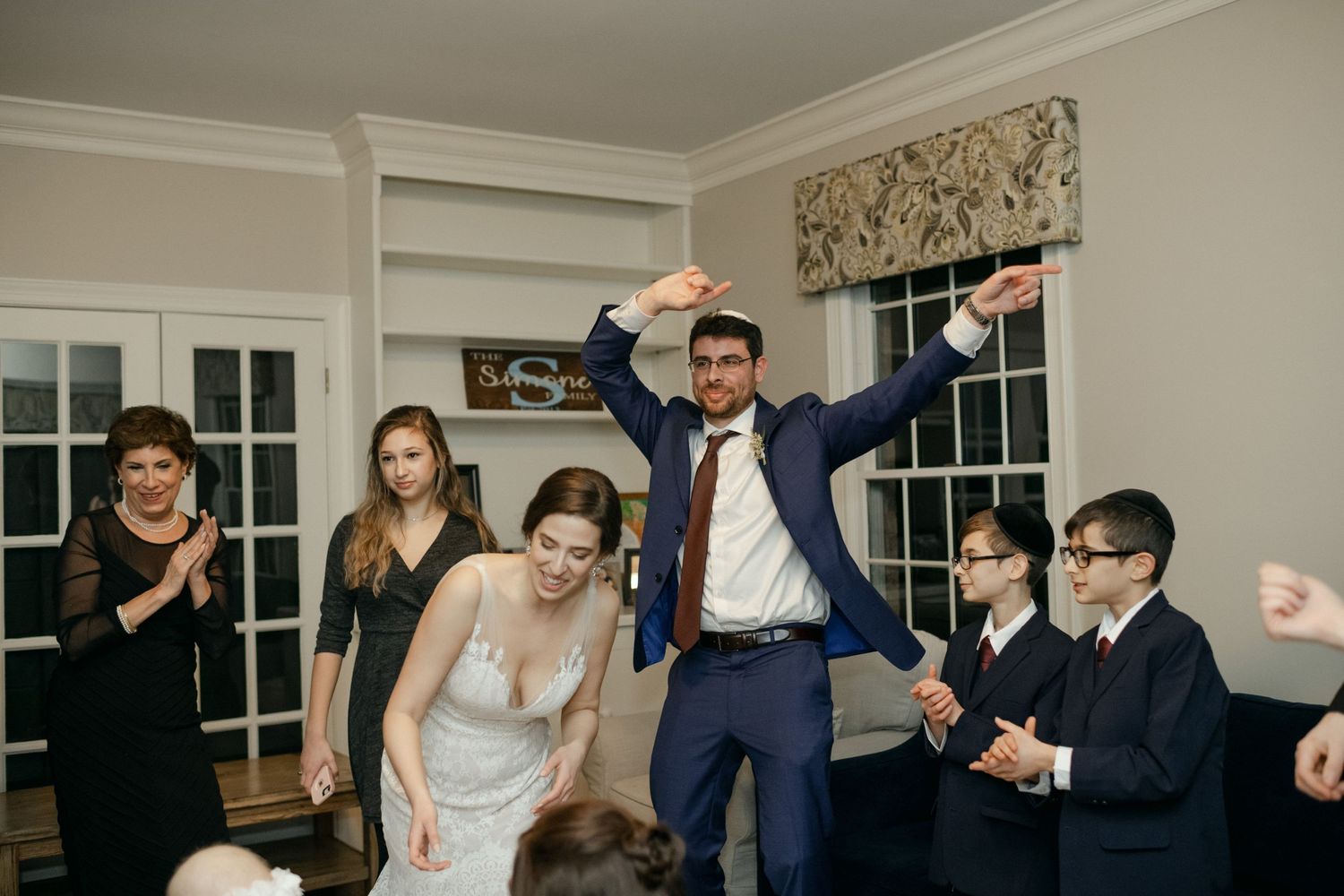 Wedding celebration with guests dancing and cheering at indoor reception.