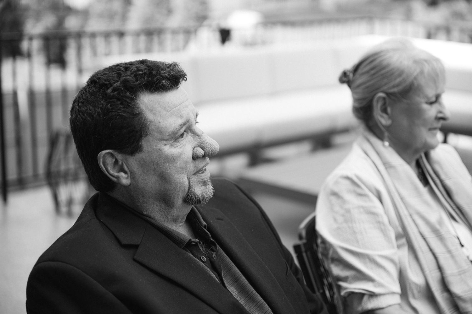 A black and white photograph showing two people sitting outdoors at an event.