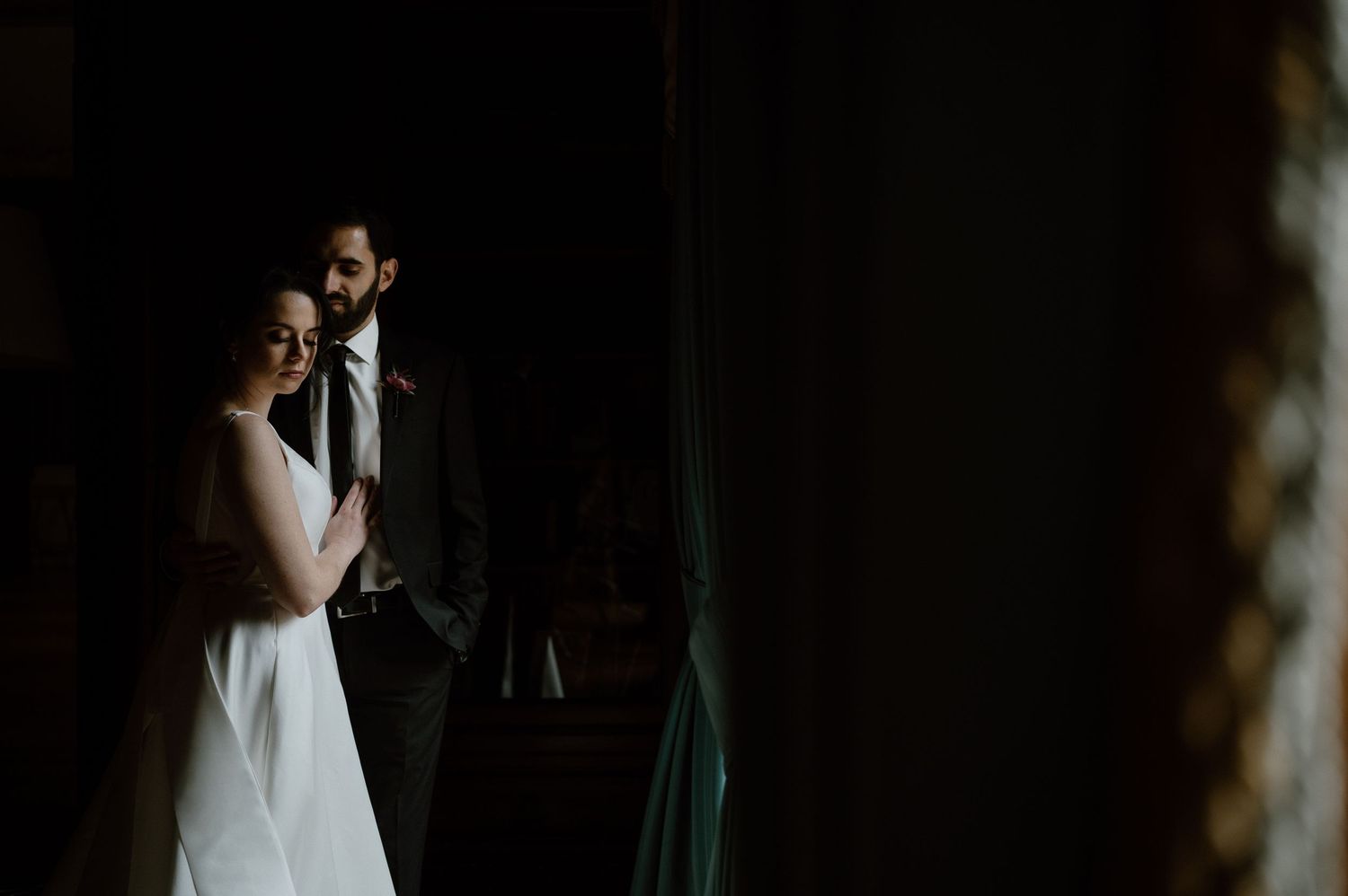 Moody and intimate wedding portrait in dark setting.