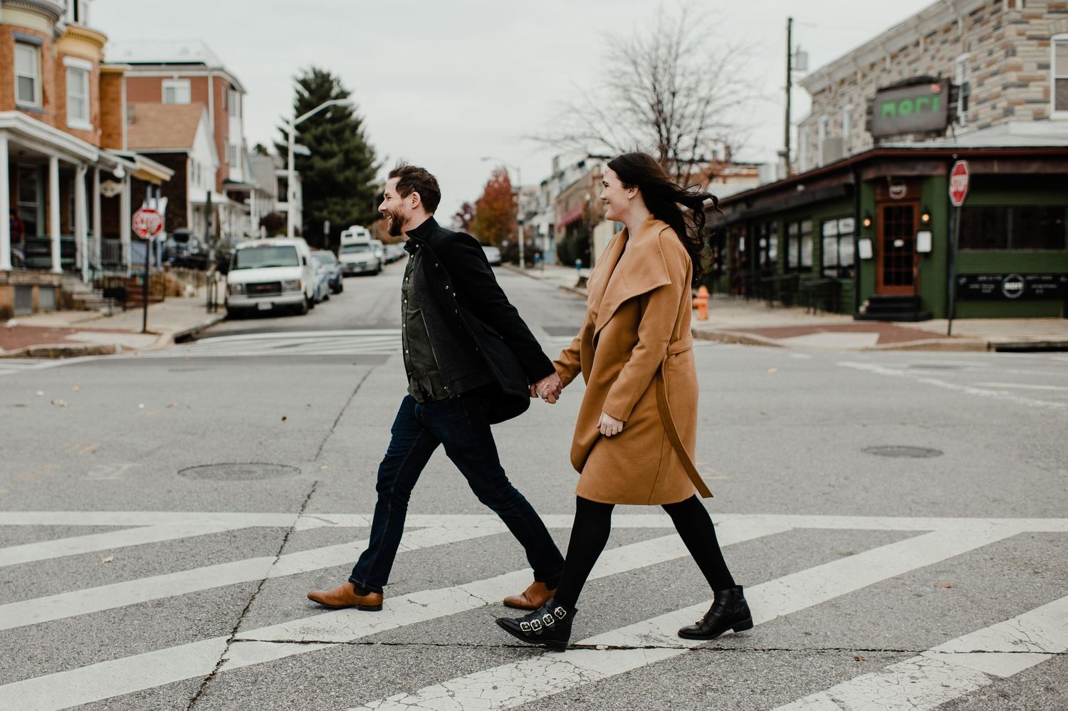 Couple holding hands crossing a zebra crossing in a charming small town street during autumn.