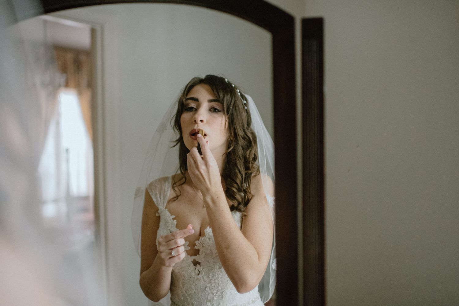 bride in mirror putting on lipstick