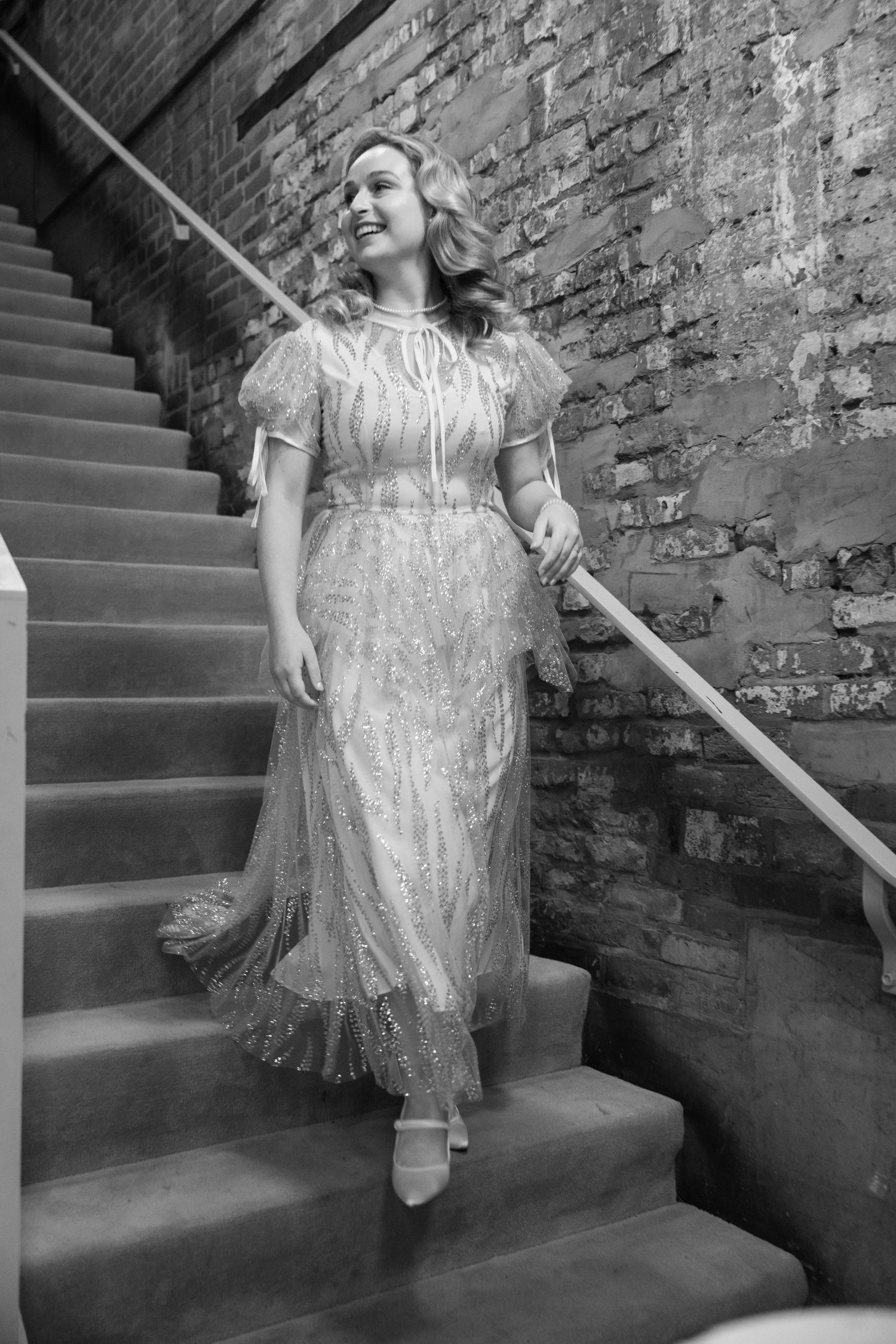 A vintage-inspired wedding dress with lace details is showcased on elegant stone steps.