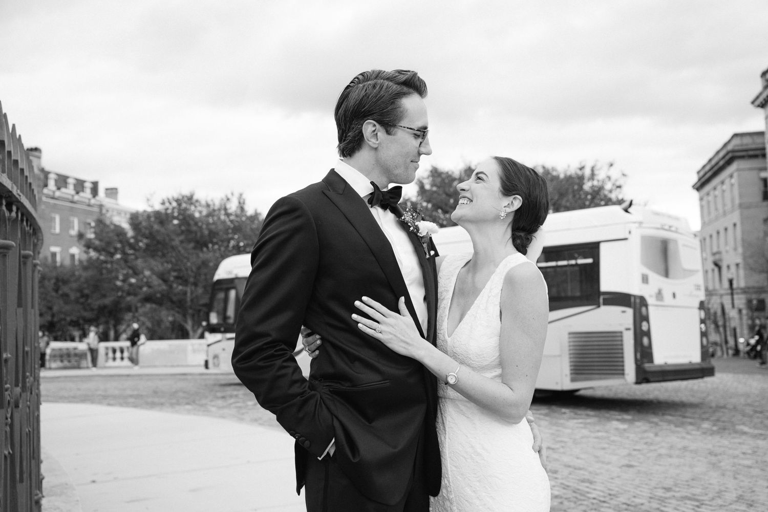 A romantic black and white portrait of a newlywed couple embracing outdoors.