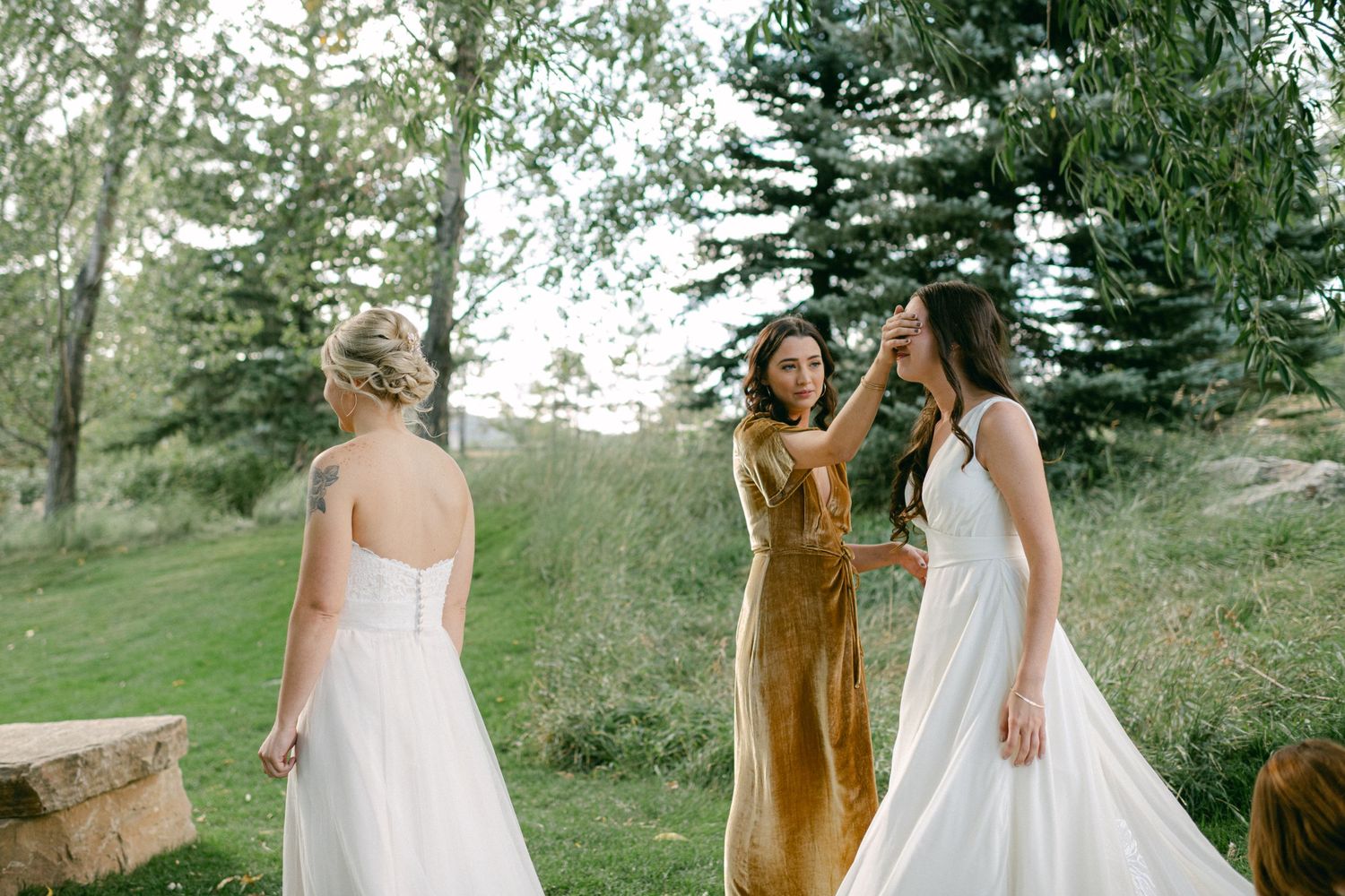 Women in white and gold dresses celebrating in outdoor garden setting.