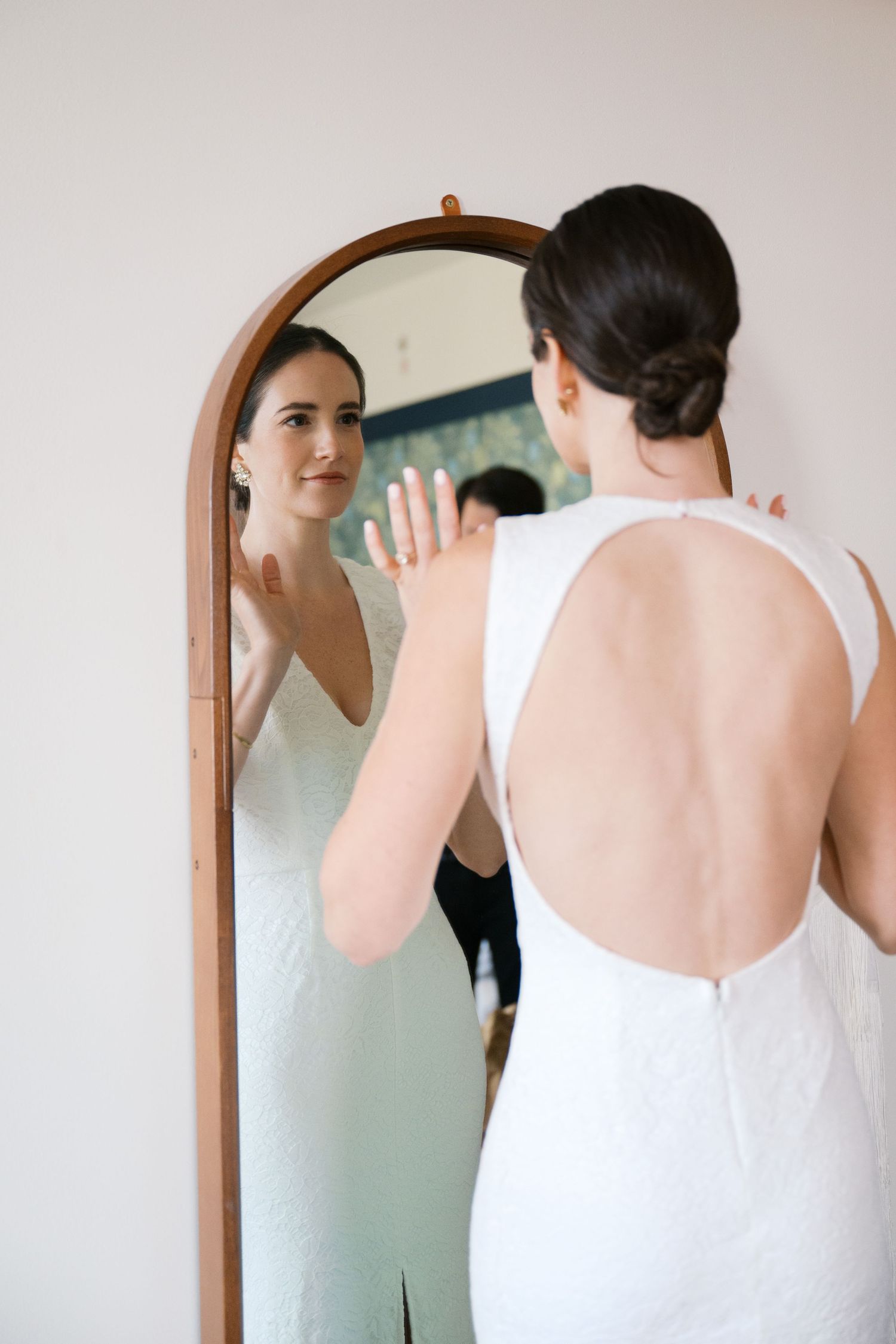 Elegant white wedding dress with open back detail shown in mirror reflection.