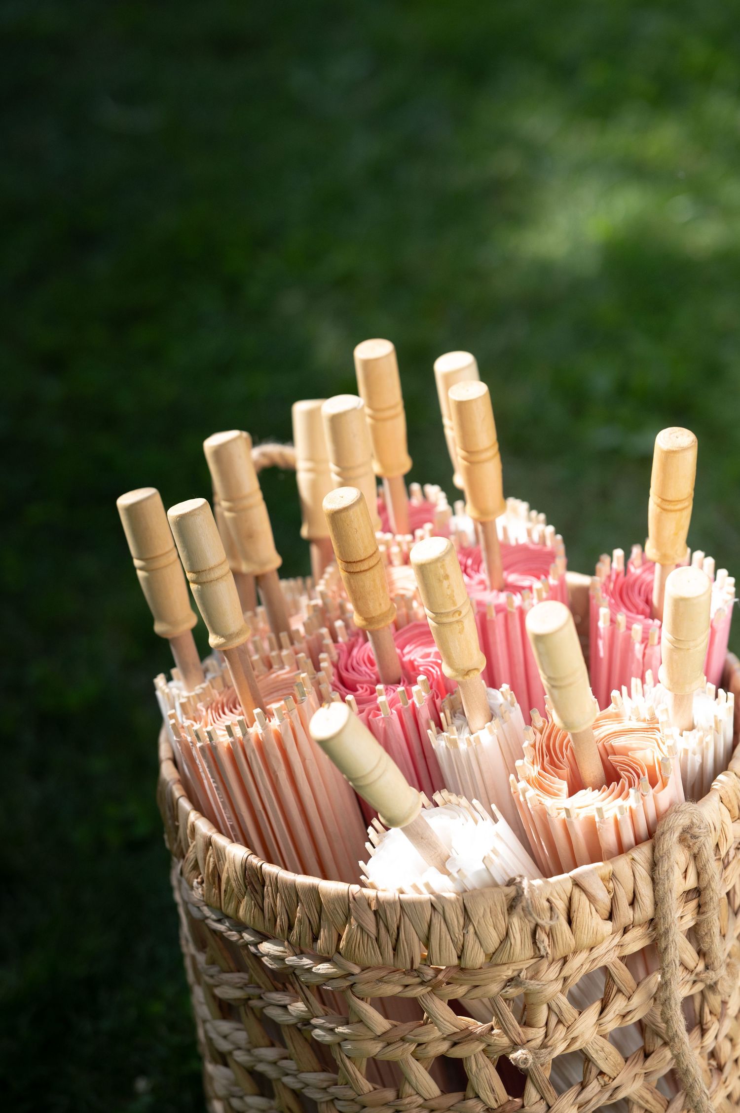 Decorative paper parasols and straws arranged in a woven basket for a wedding.