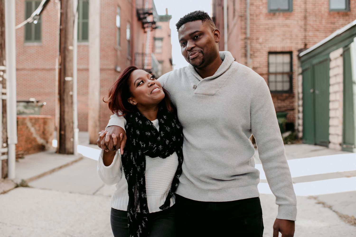 A candid outdoor portrait of a couple laughing together on a city street.