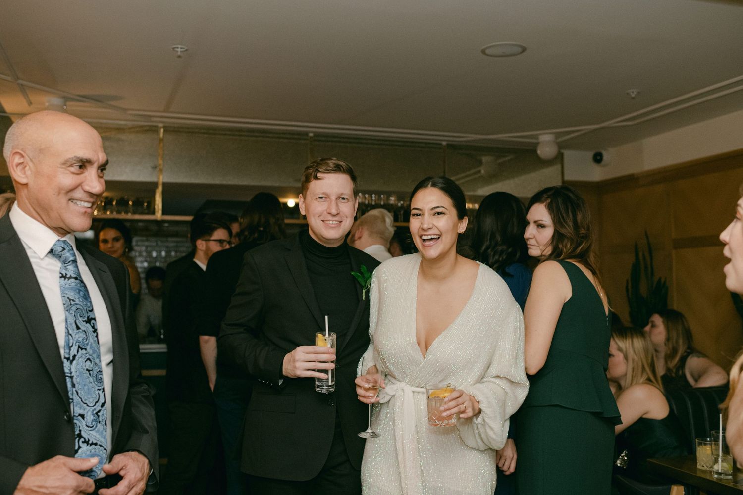 Guests mingling at an indoor celebration event with drinks.
