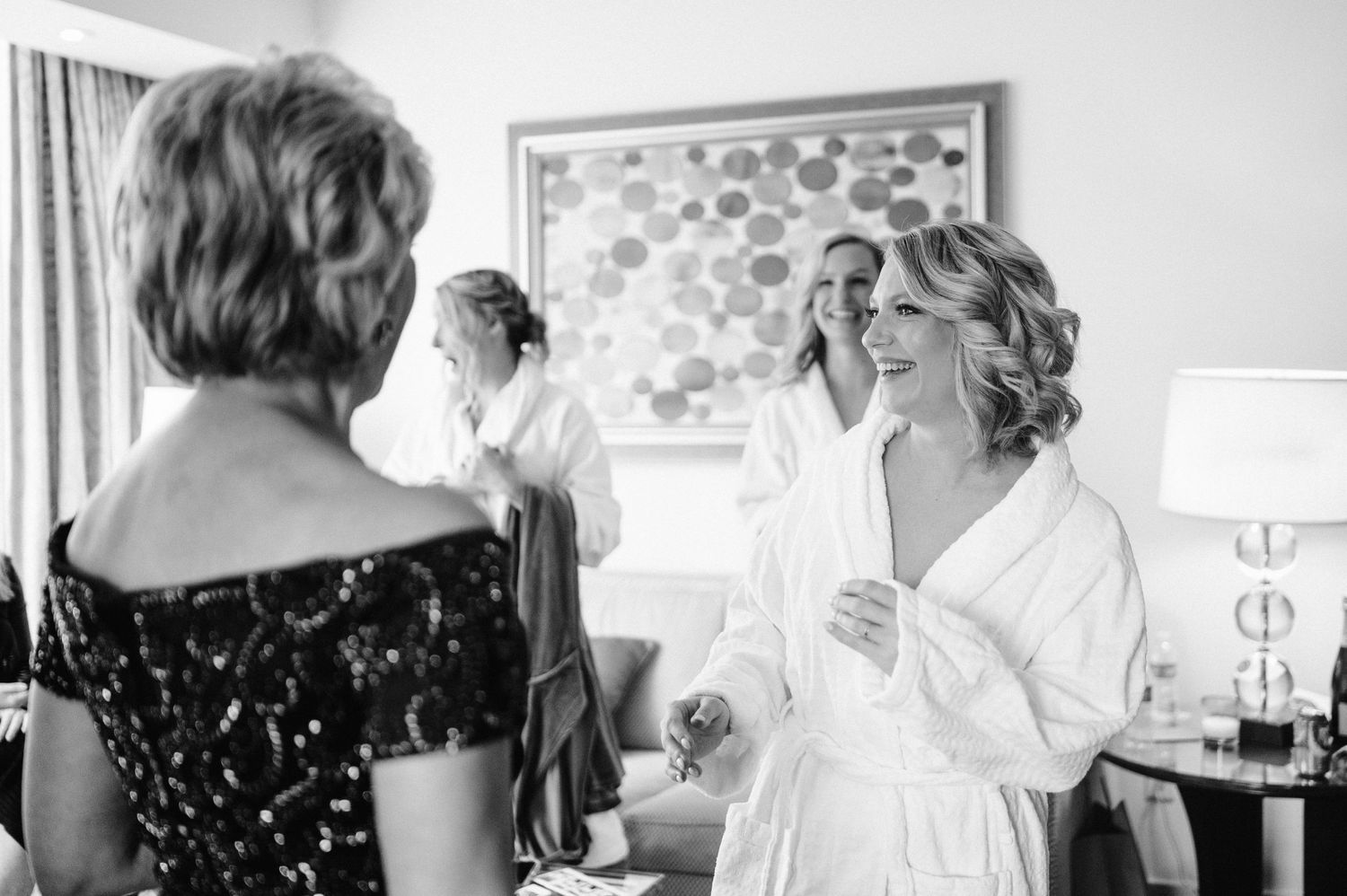 Black and white photo of wedding preparation scene in a hotel room with elegant attire.