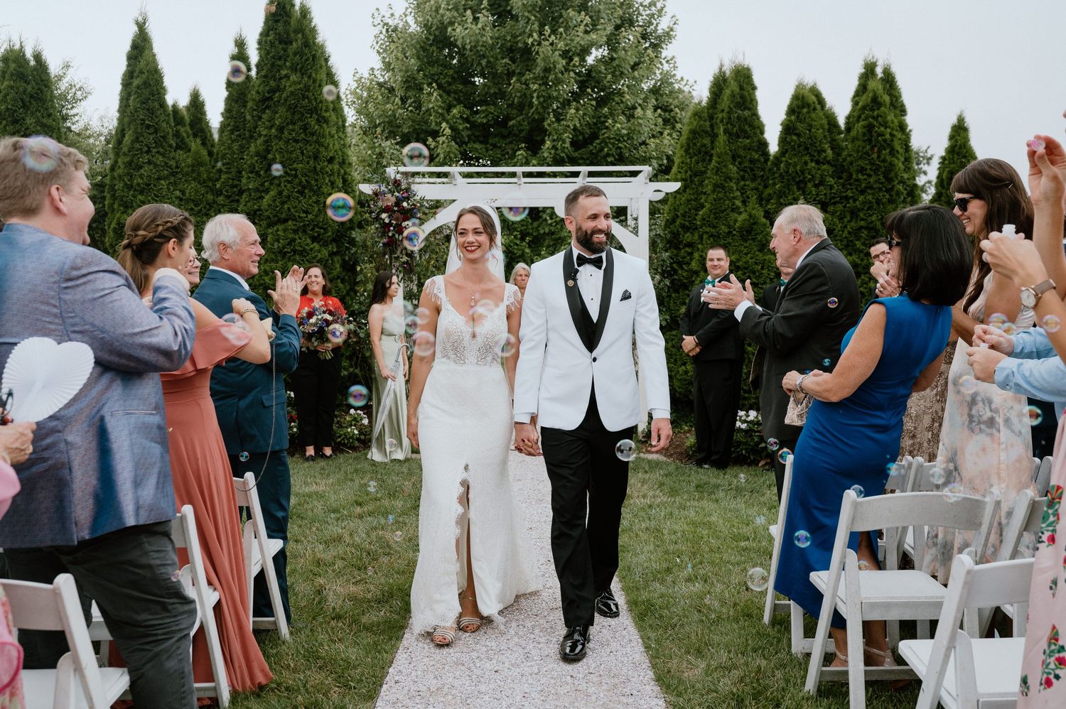 Guests celebrate as a couple walks down an outdoor aisle after their ceremony.