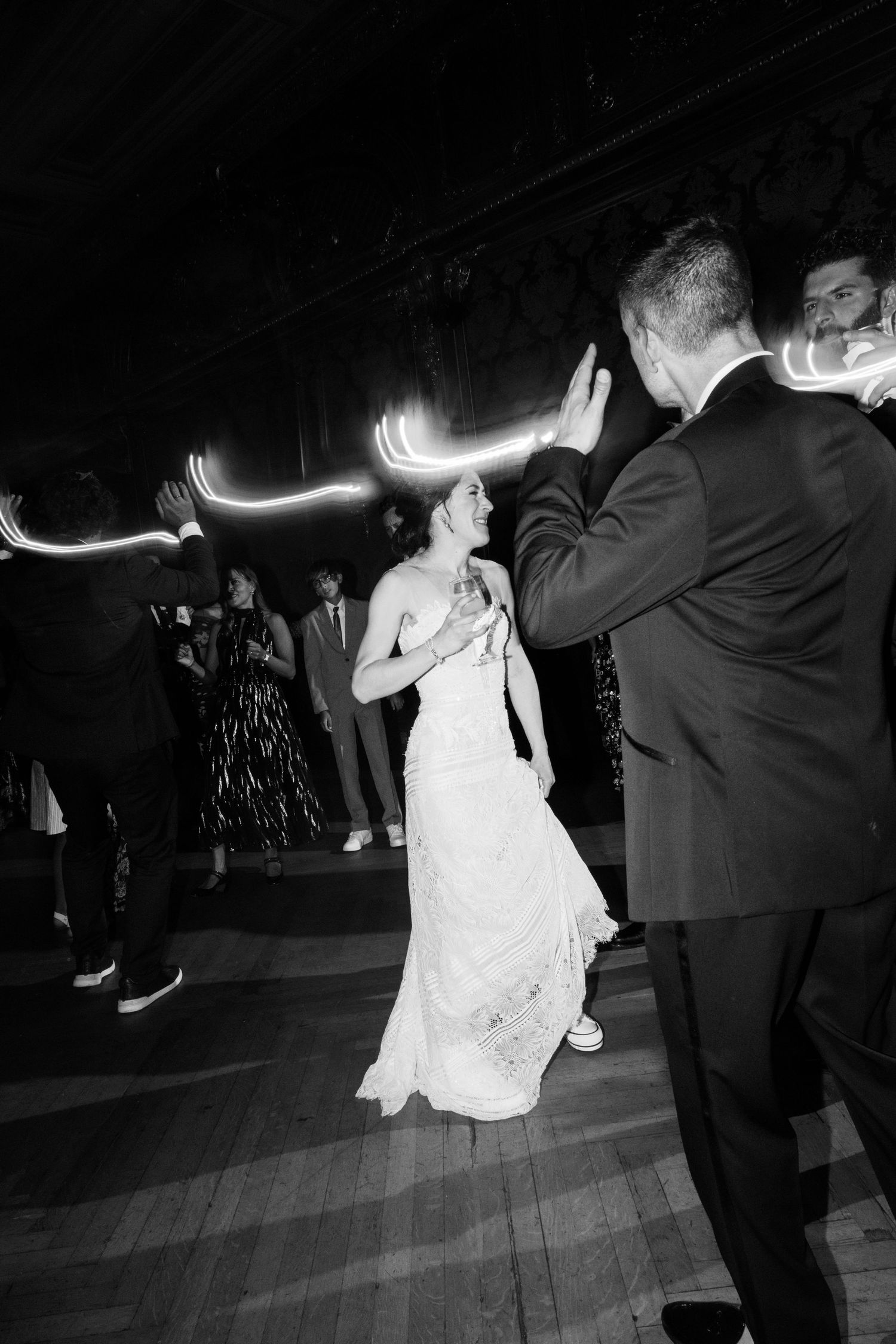 A couple performs a lively dance move in a dimly lit room with dramatic lighting effects casting shadows.