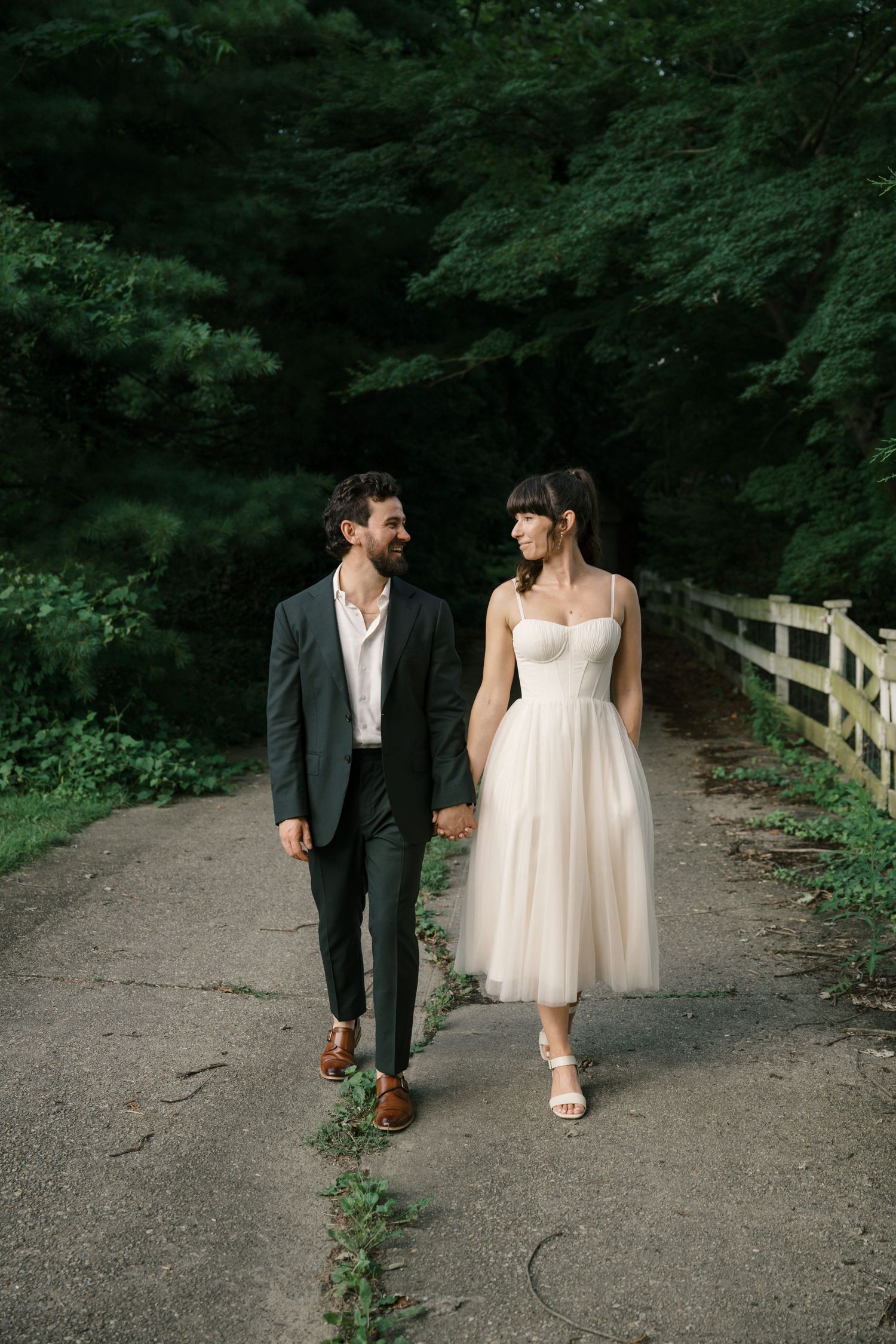 Wedding couple walking together on a wooded path showing cropped view of their formal attire and footwear.