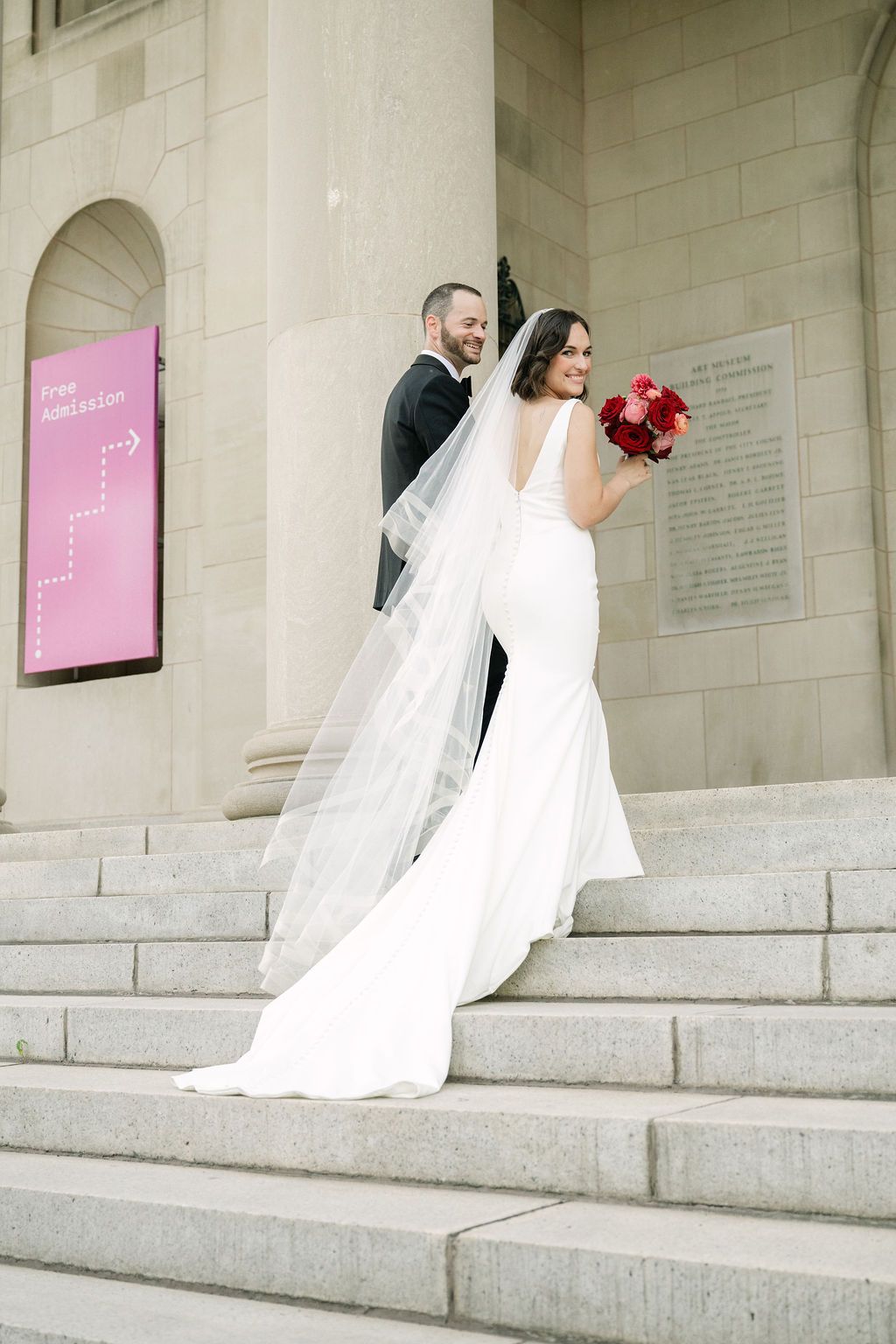 A wedding couple descends stone steps outside a building in a series of progressive shots showing their movement downward.