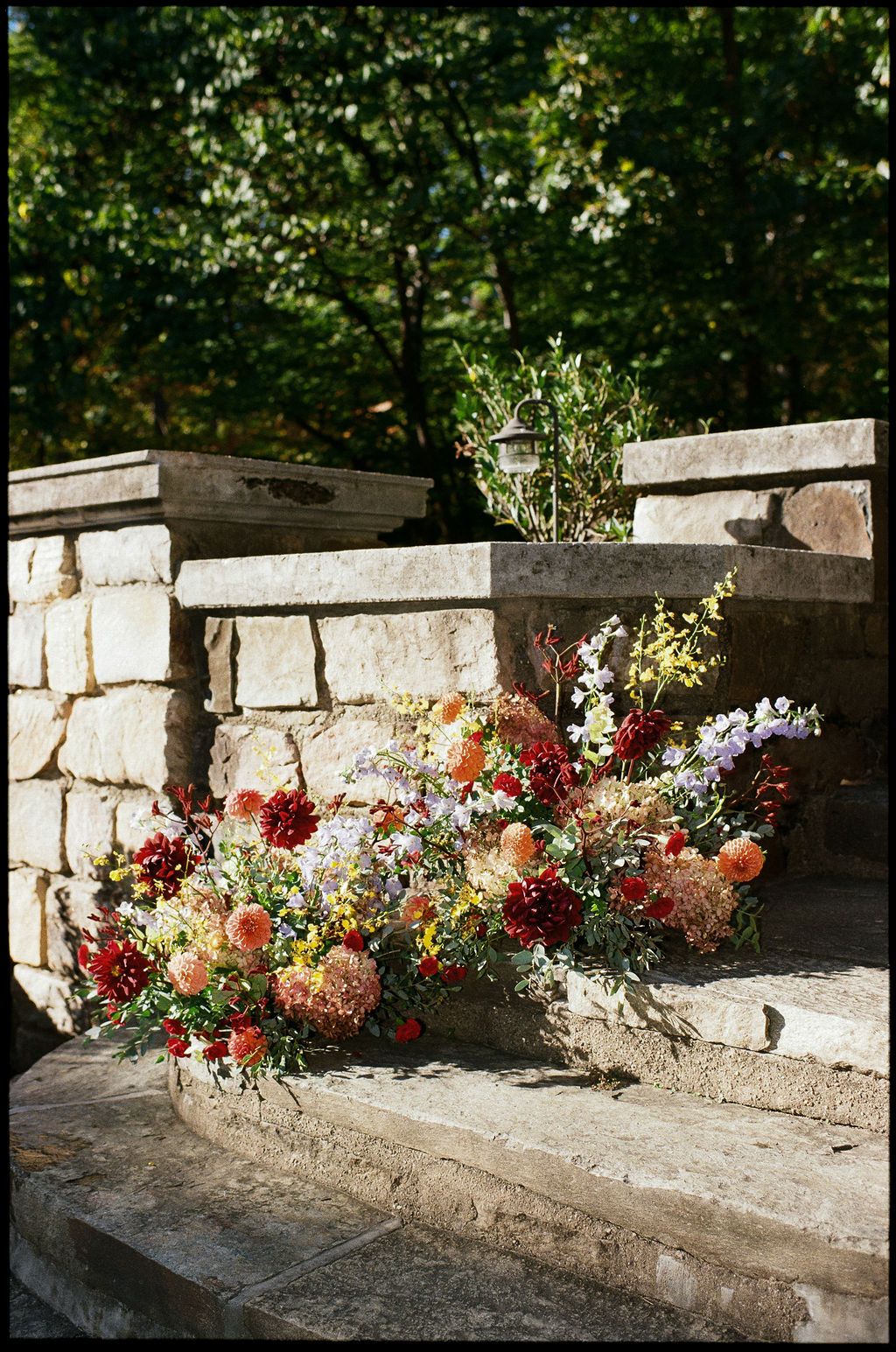 Colorful floral arrangements decorating a stone wall at an outdoor venue at Strong Mansion on Sugarloaf Mountain