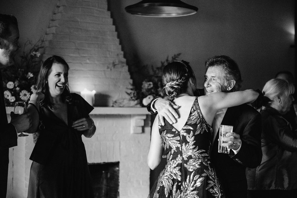 Black and white photo of guests laughing and embracing at an evening celebration Fadensonnon in Baltimore