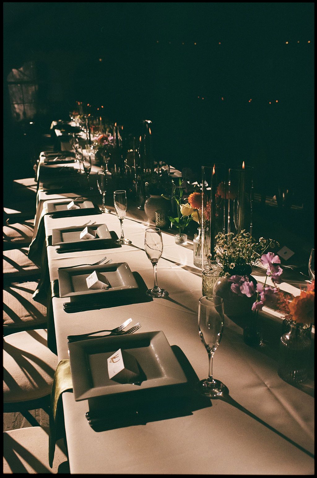 Dramatic evening shot of formal place settings at an elegant reception dinner at Strong Mansion on Sugarloaf Mountain on film