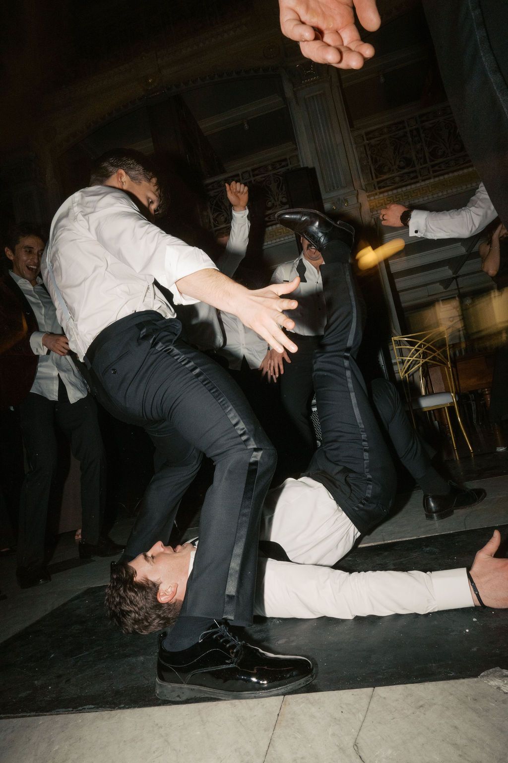 Guests performing energetic dance moves on the floor during wedding celebration.