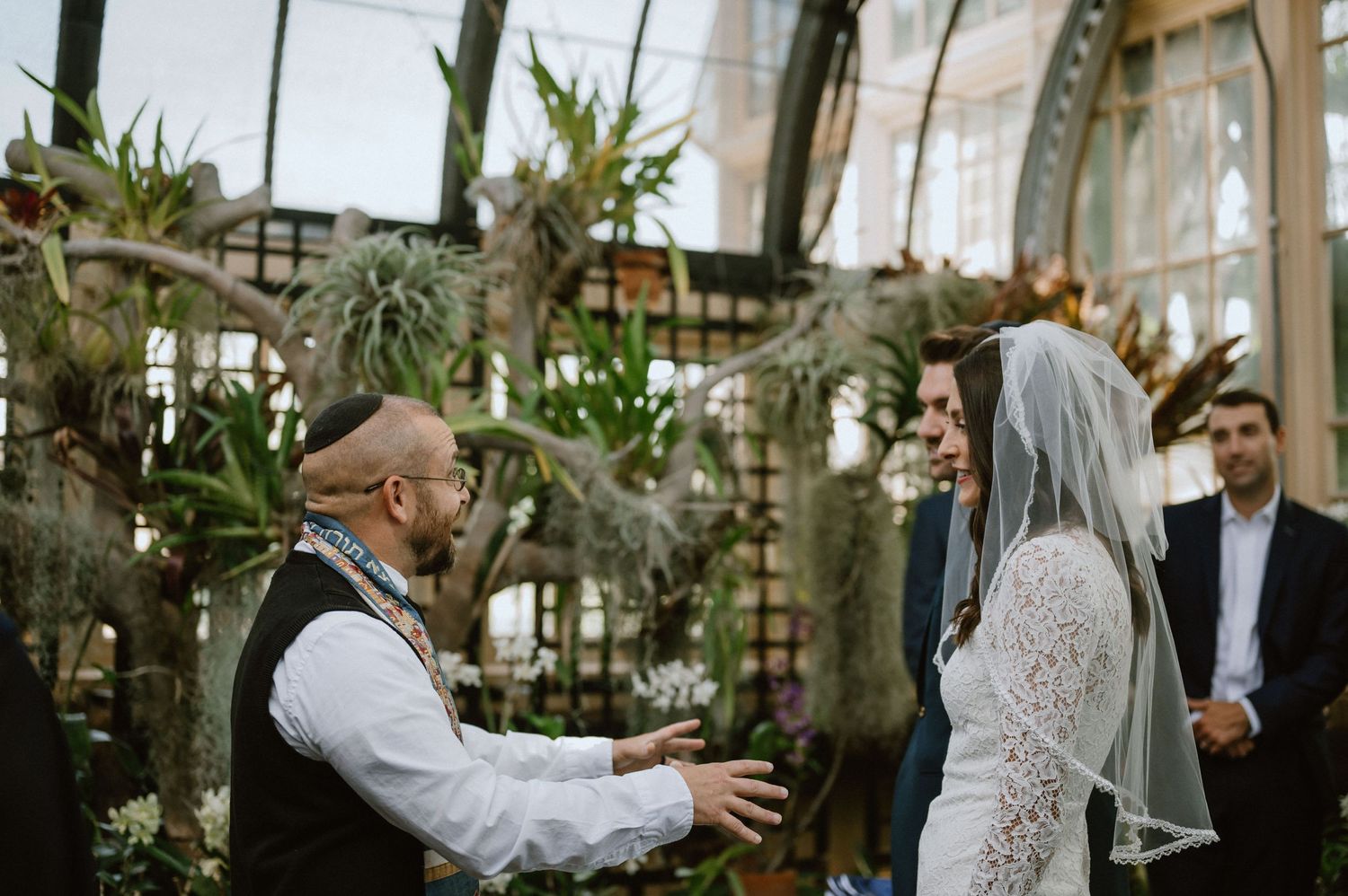 Greenhouse wedding ceremony with tropical plants and natural lighting.