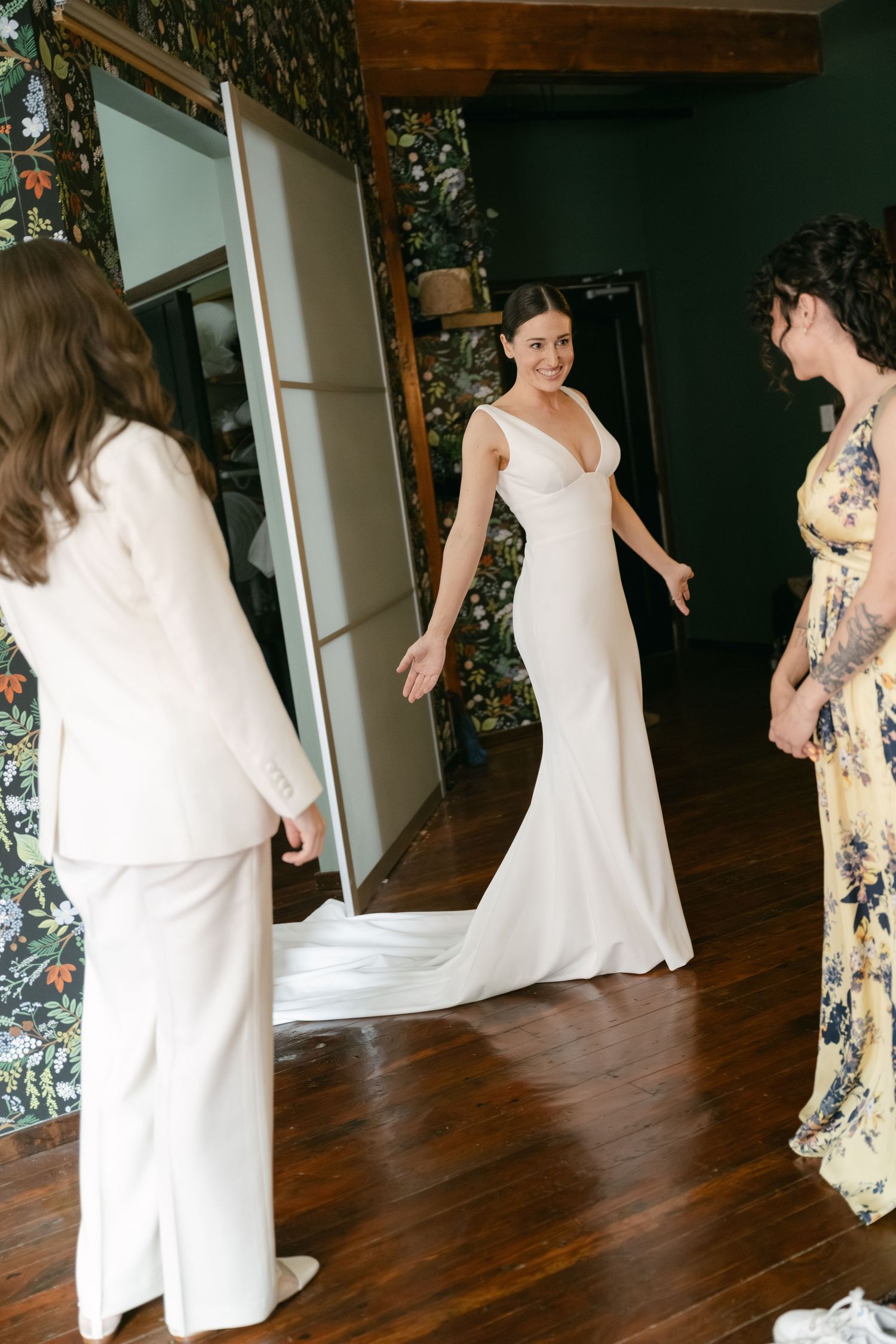 People in white dresses and floral attire dancing together in a warmly lit room.