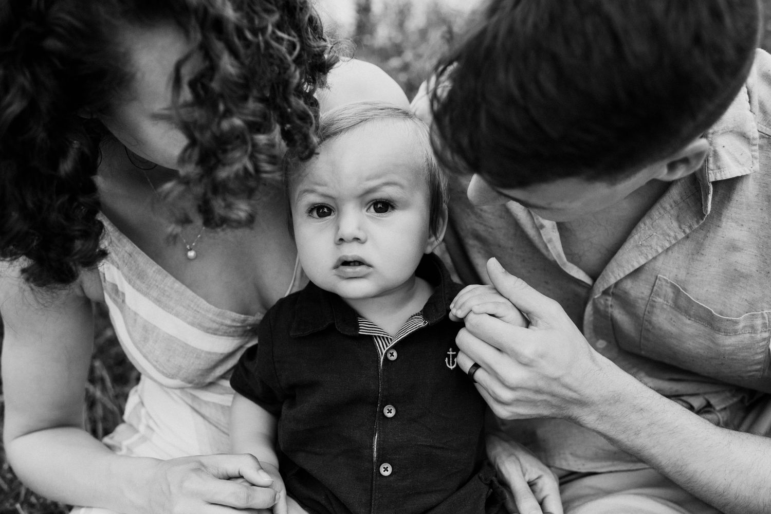 Black and white intimate family portrait with baby in center.