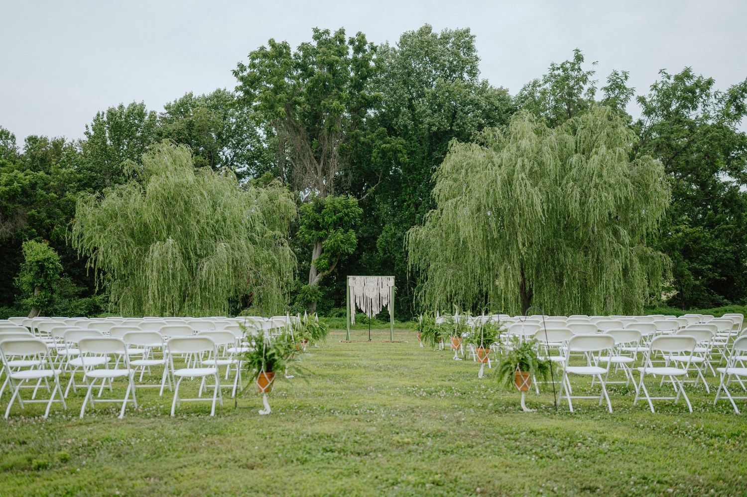 backyard wedding ceremony setup with boho altar and white chair backyard wedding maryland documentary wedding photograph