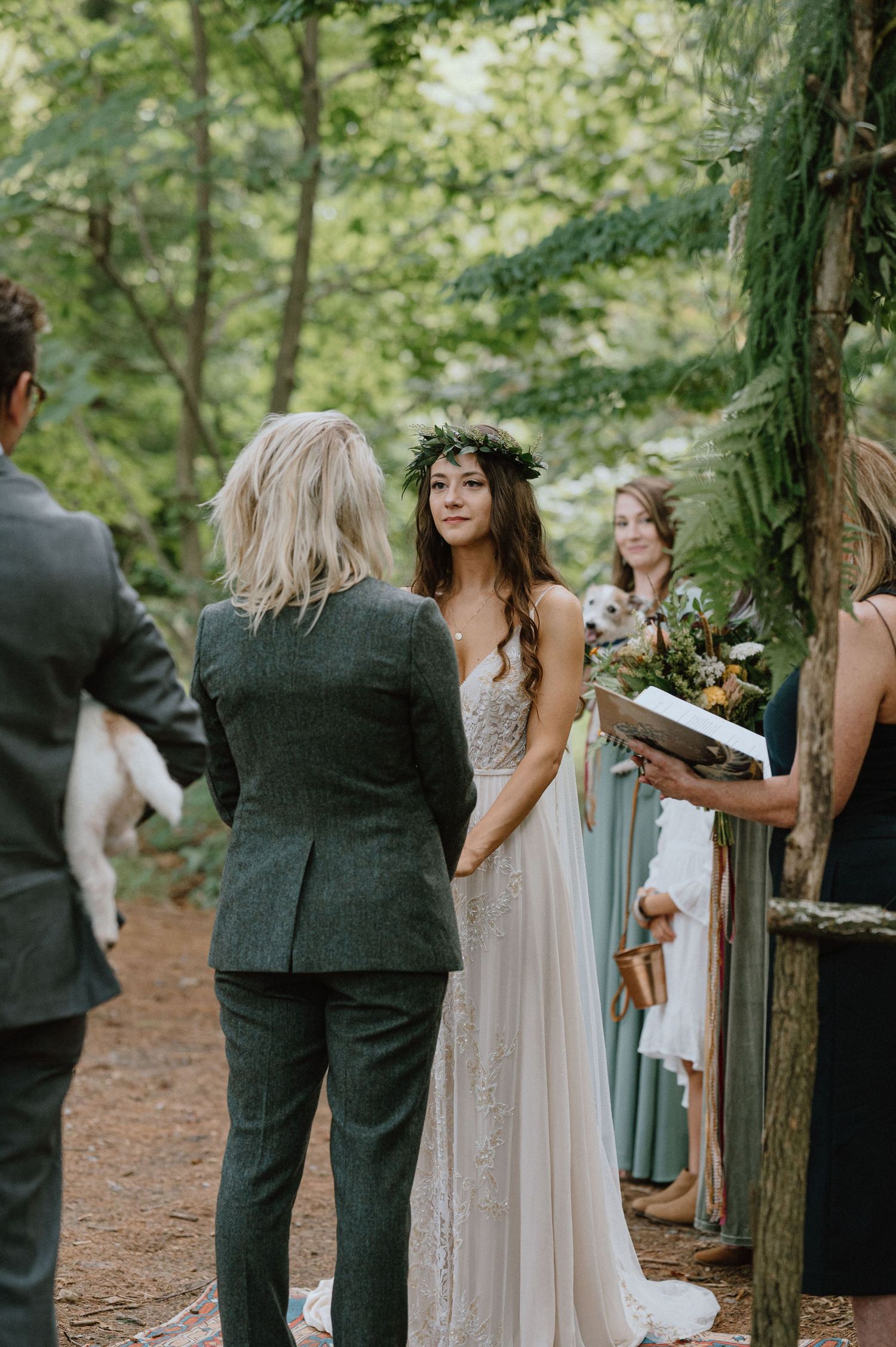 Intimate forest wedding ceremony with attendees gathered around a macrame backdrop.