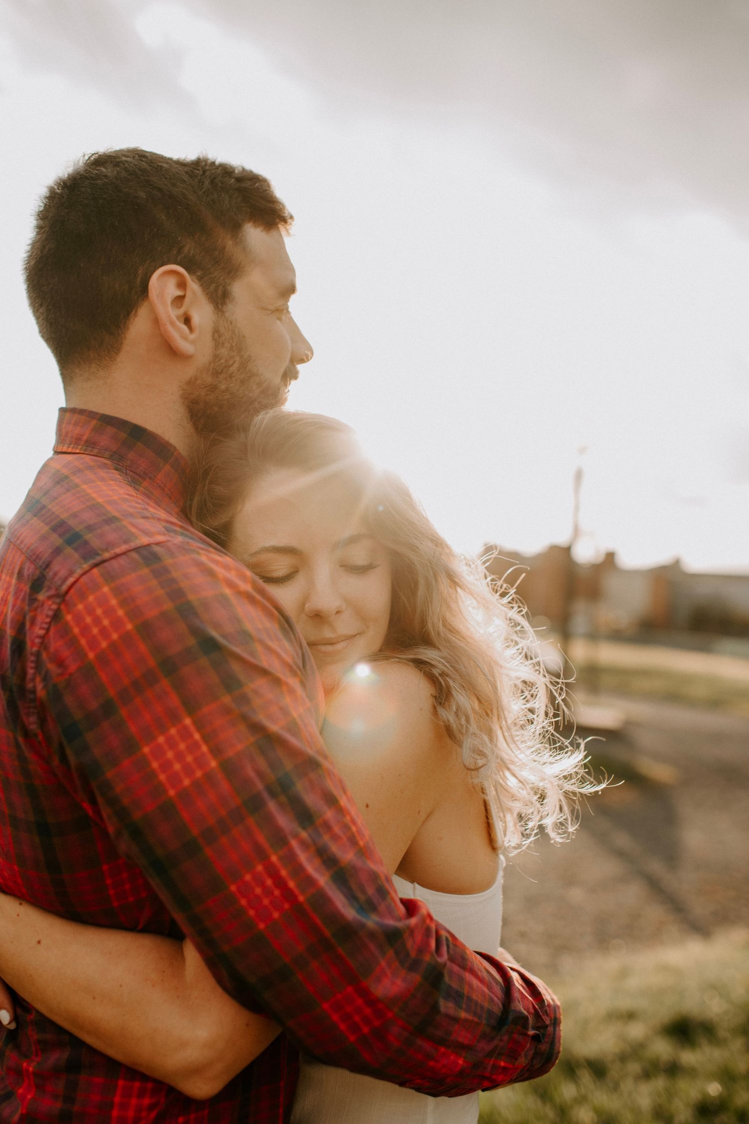 Couple embracing in warm sunset light wearing casual clothing.