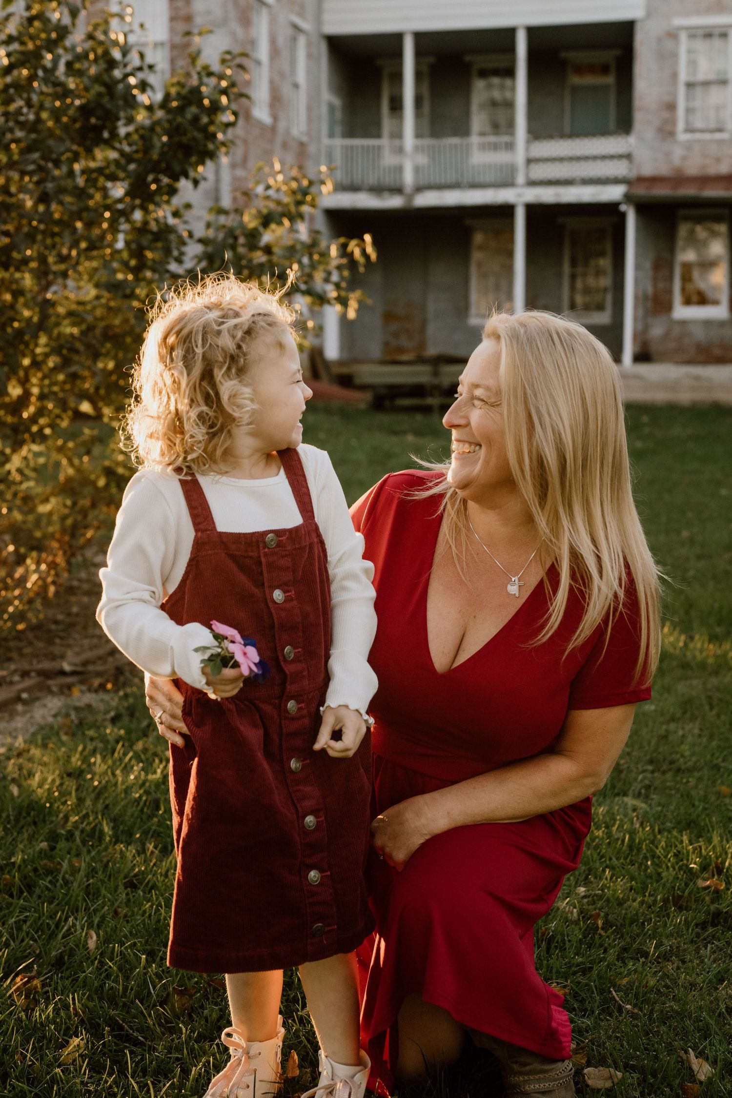 A tender moment between two people in red outfits against a sunlit building backdrop.