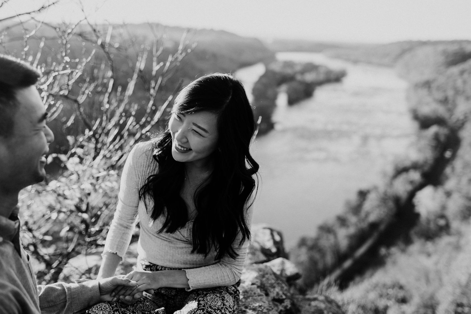Black and white photo of couple sharing joyful moment on scenic overlook.