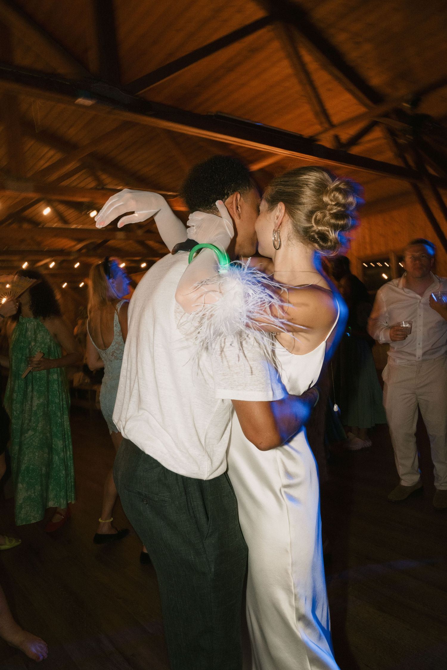 Intimate slow dance moment captured under wooden beams with blue ambient lighting.
