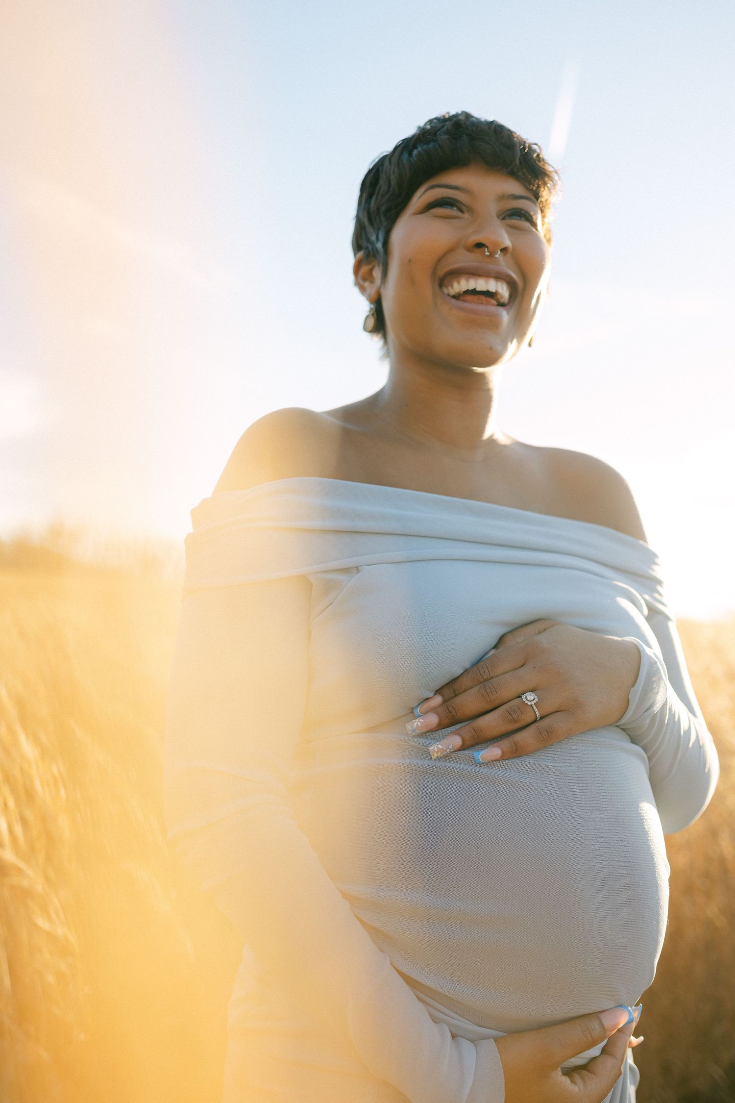 maternity photo of woman holding baby bump laughing in maryland