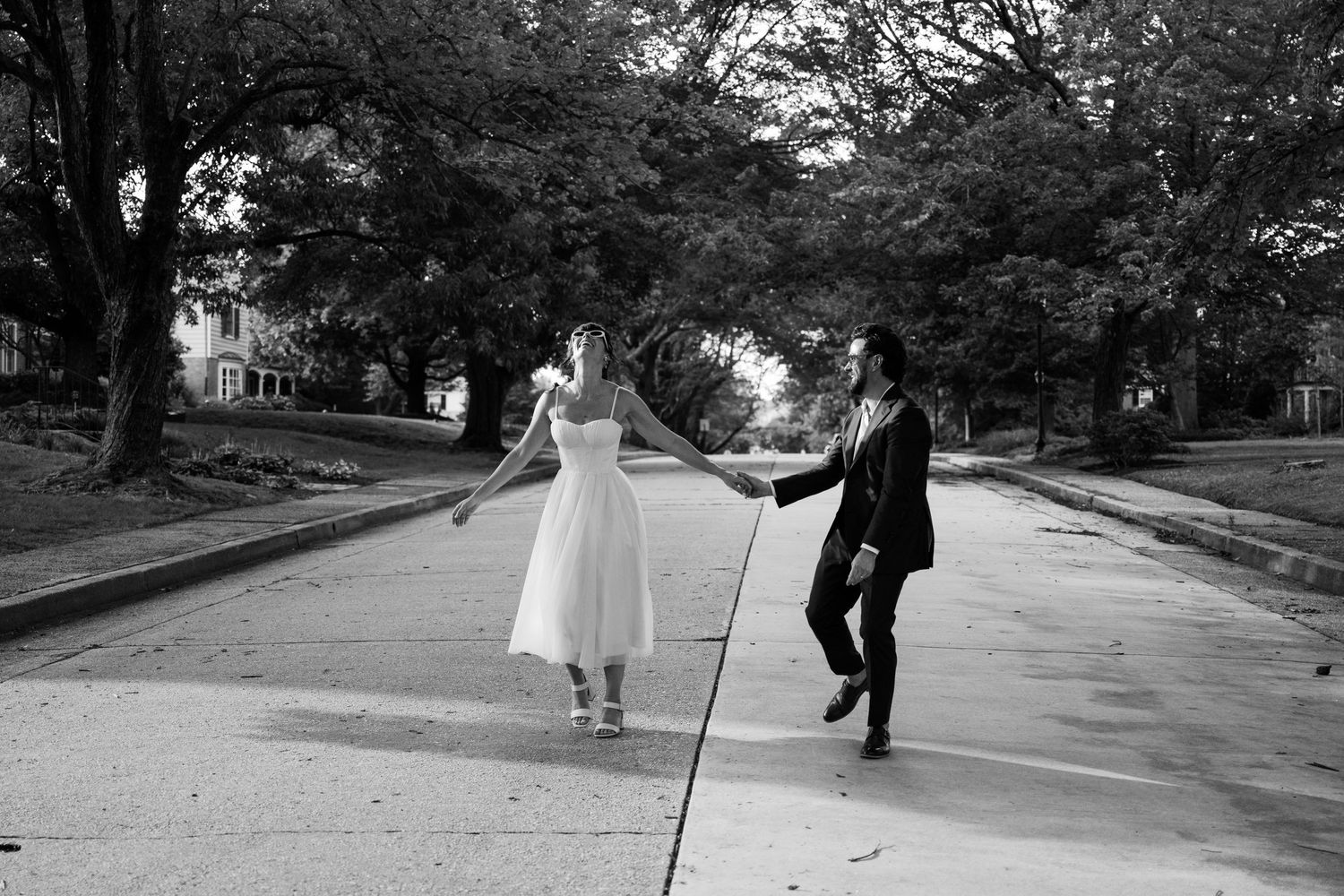 Couple walking along a tree-lined path in a romantic outdoor setting.