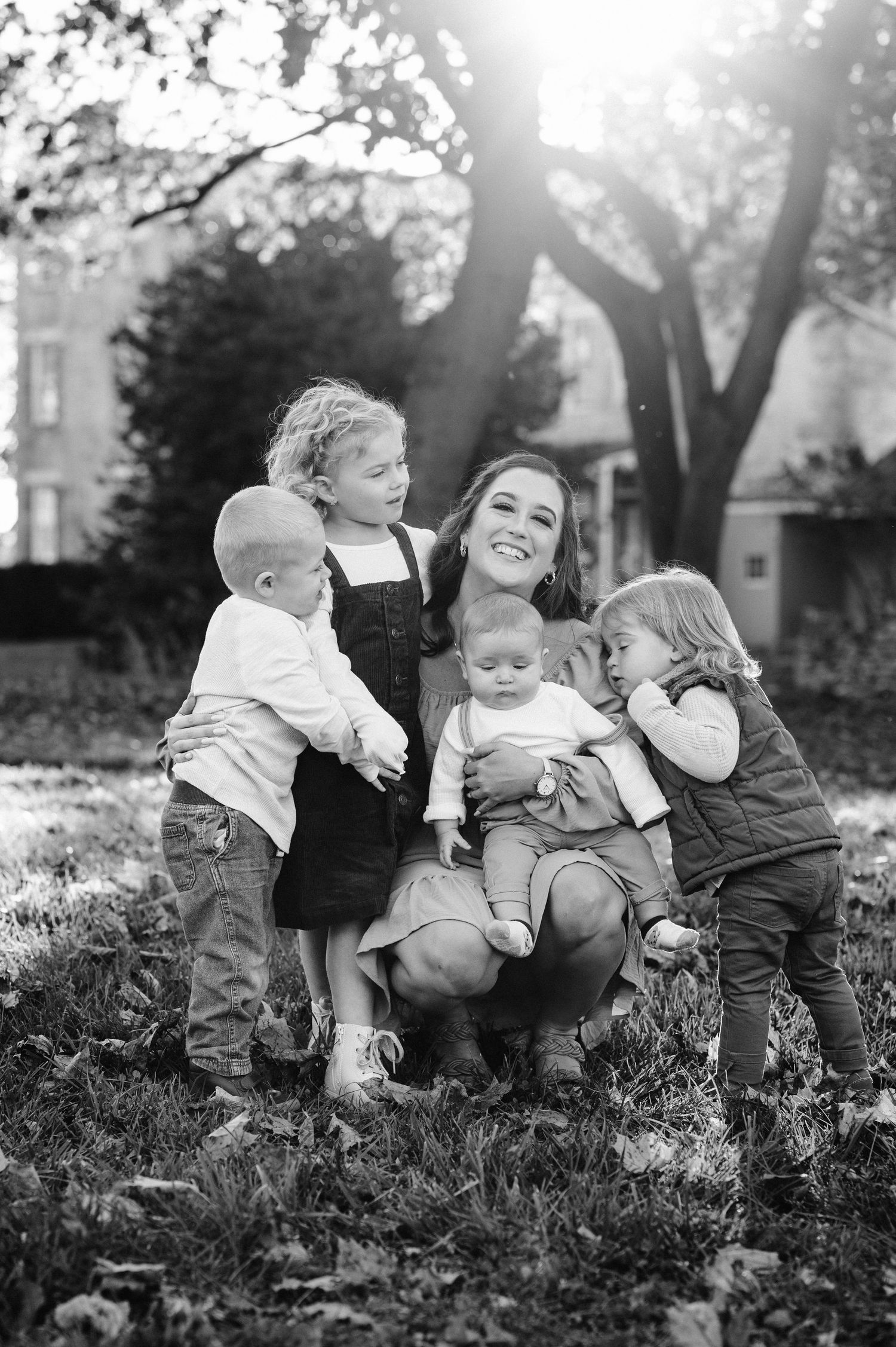 Black and white portrait of family group sitting together on grass.