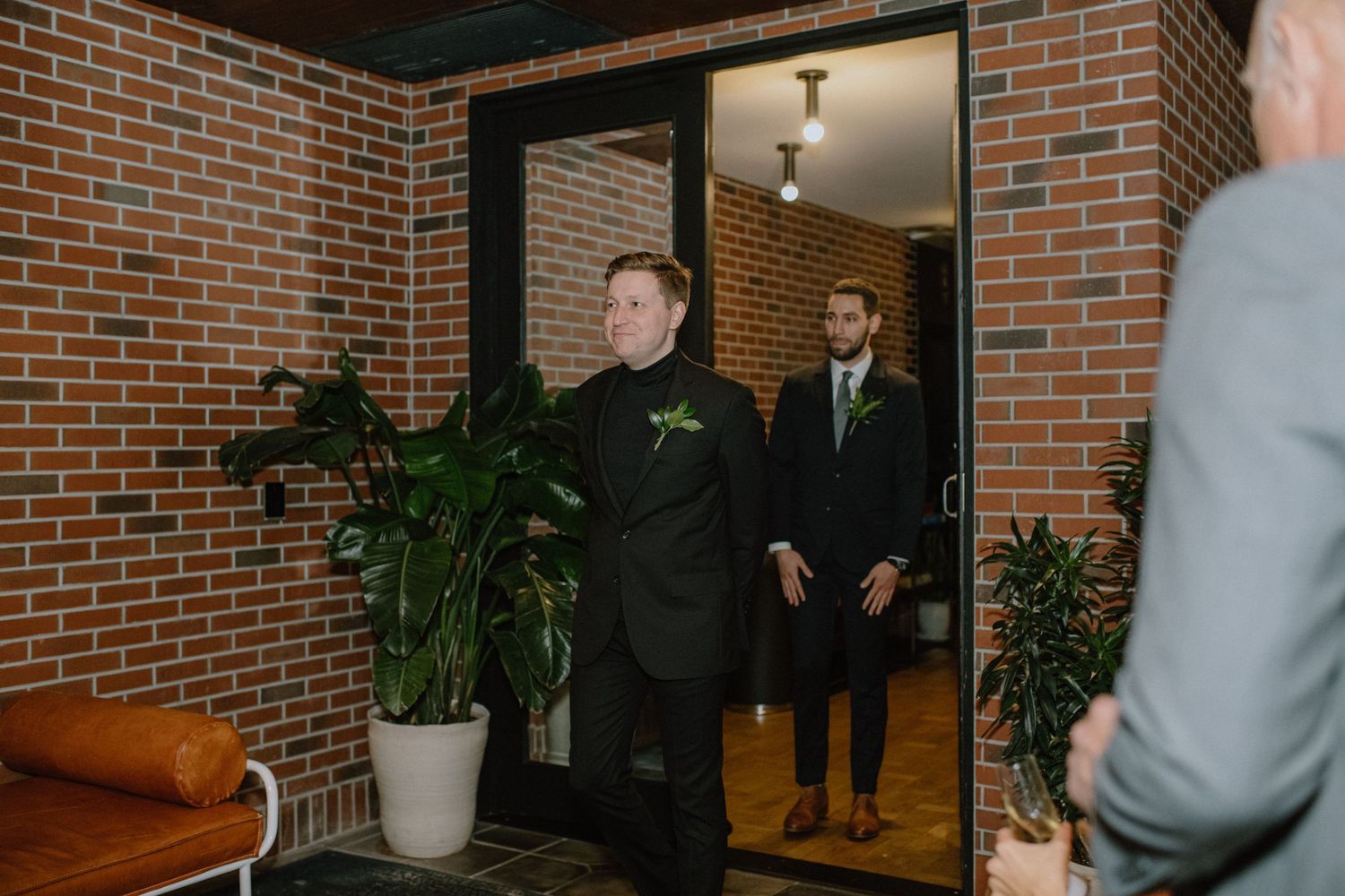 Formal gathering in brick-walled entrance with indoor plants.