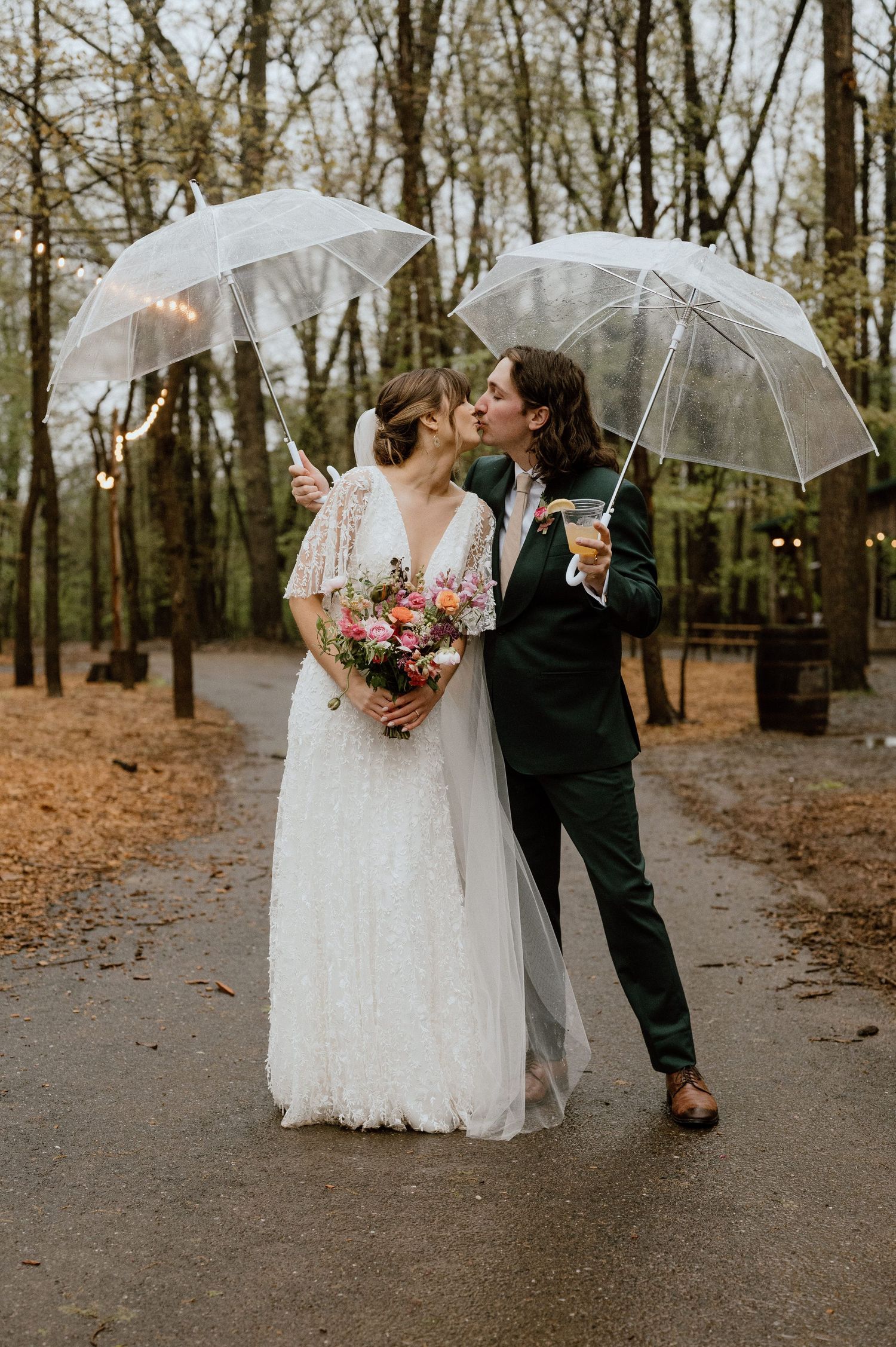 A romantic wedding portrait of a couple with clear umbrellas in a forest setting.