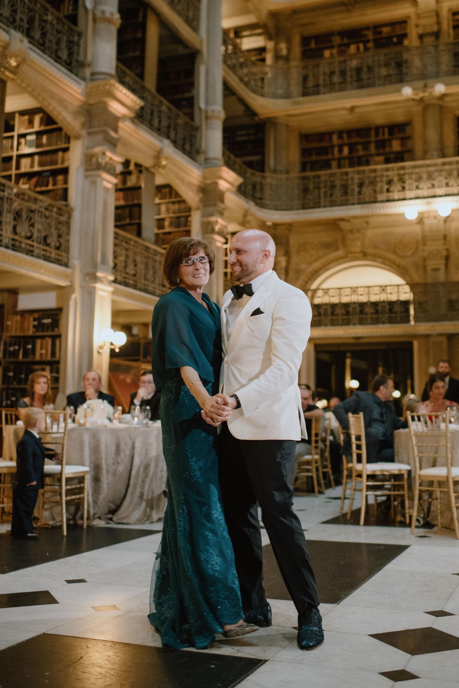 Wedding dance between two guests in an ornate library with multiple levels of bookshelves.