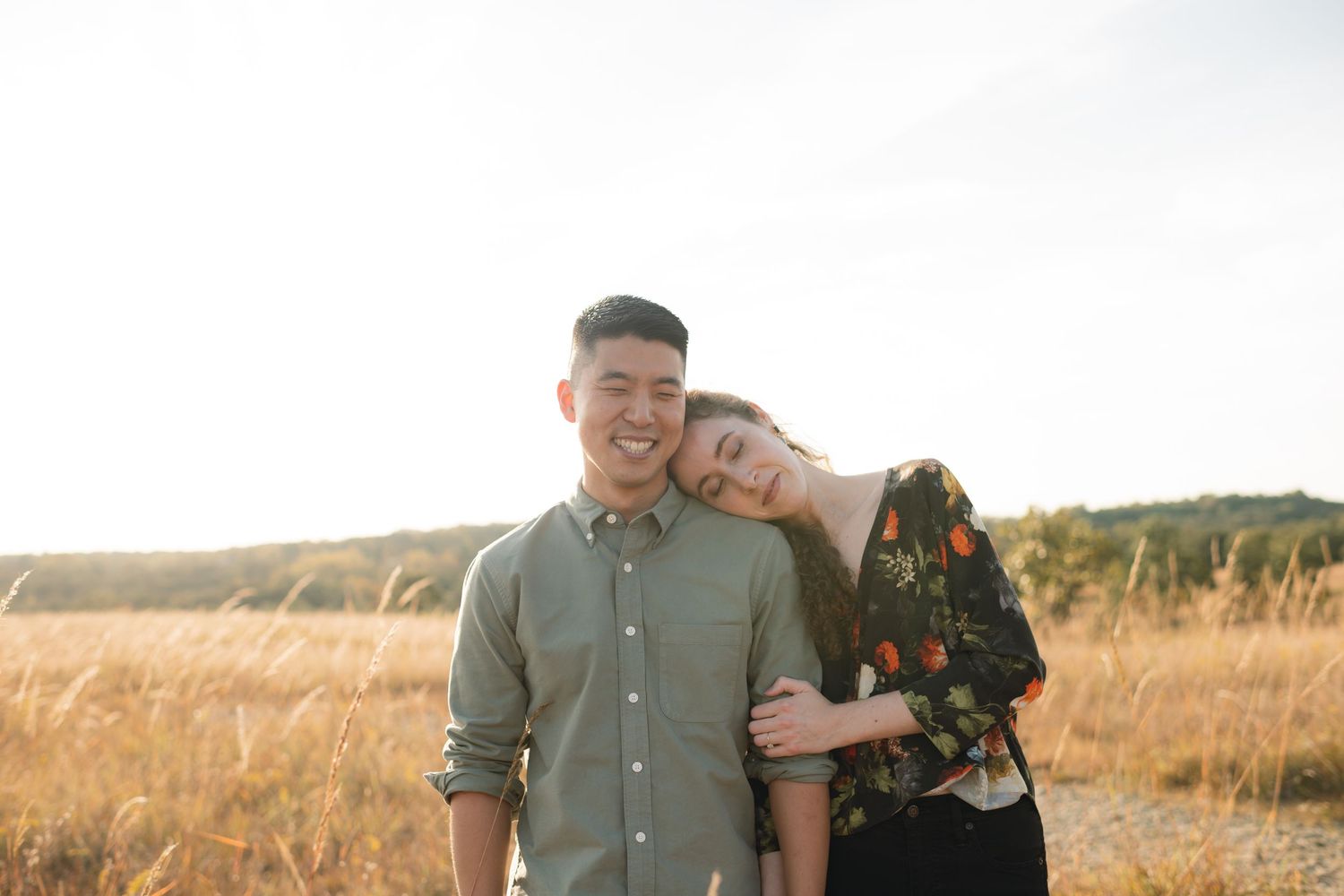 A tender moment between a couple in a sunlit prairie field.