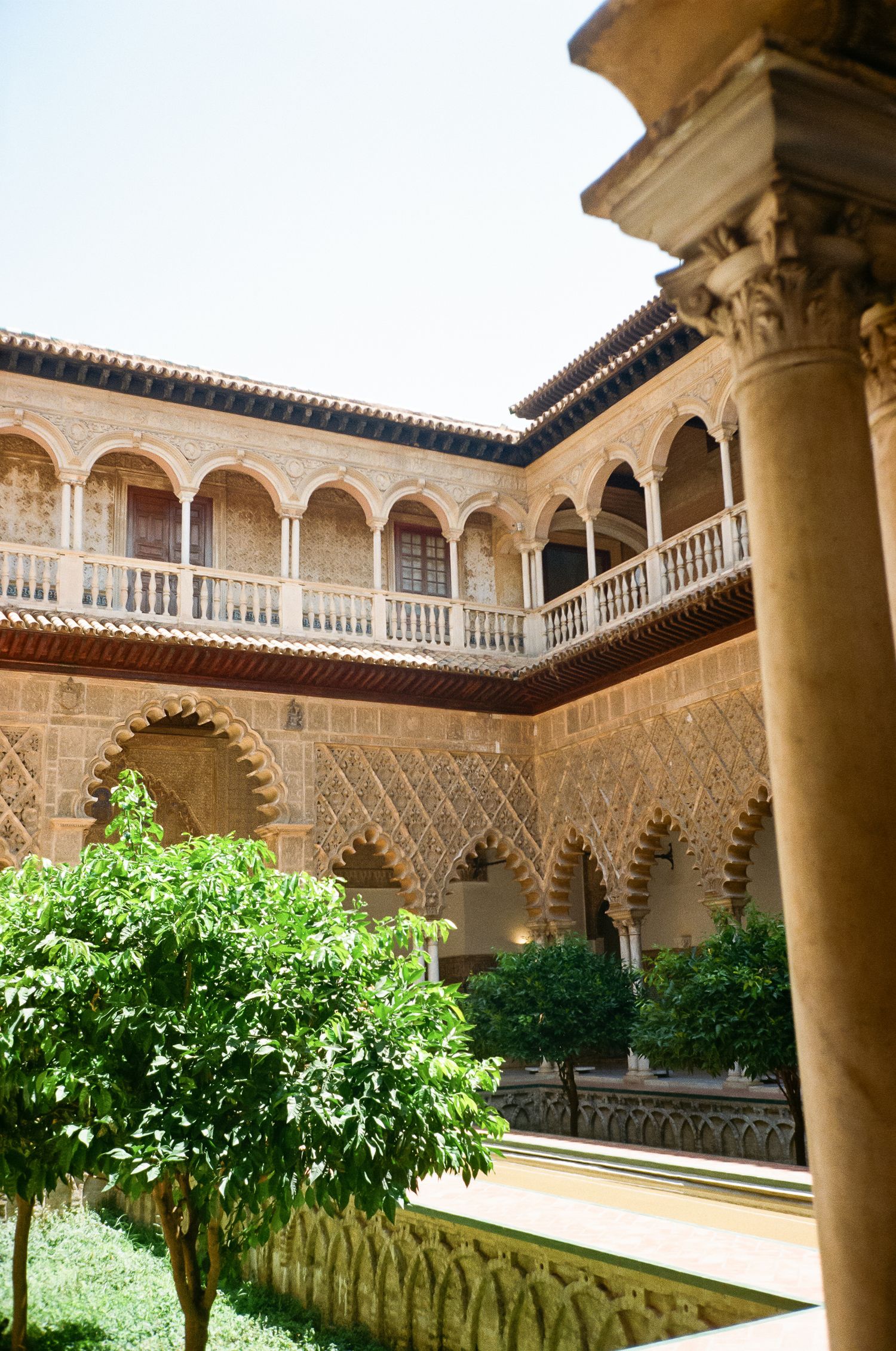 Moorish courtyard with ornate arches and columns surrounding a garden in traditional Spanish architecture.
