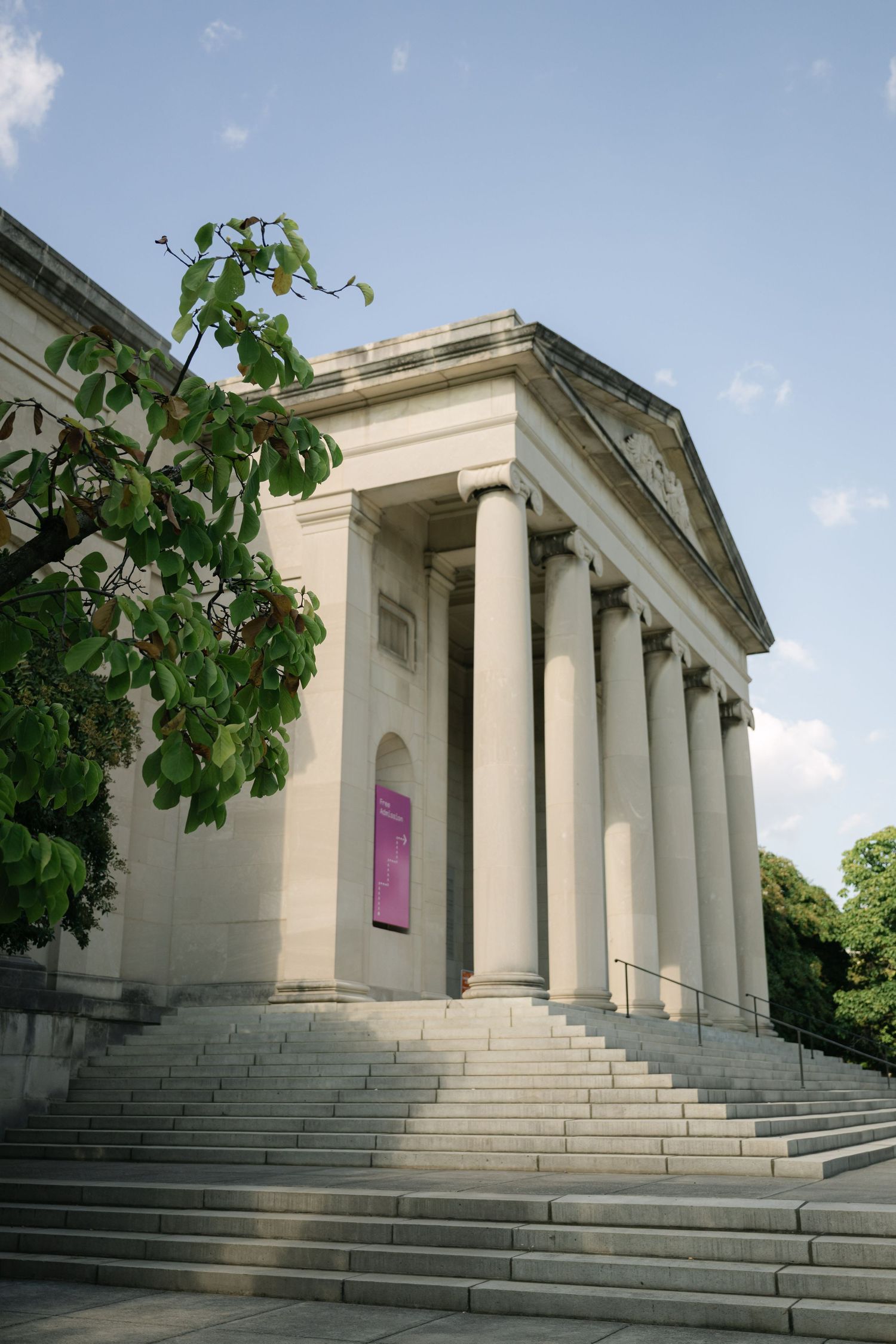 Neoclassical building exterior with grand white columns and wide stone steps leading to entrance.