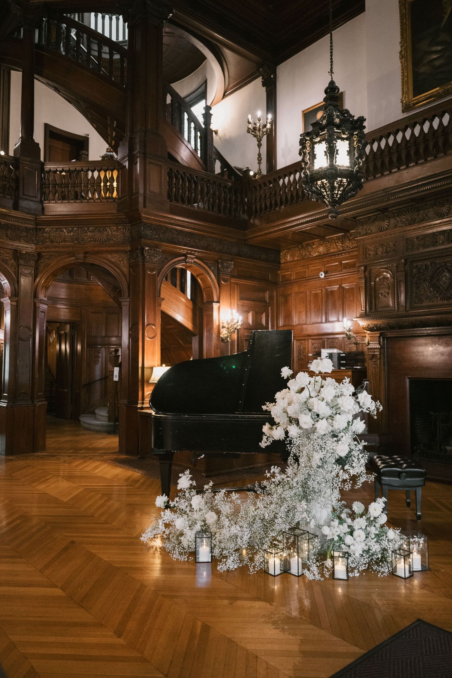 Luxurious white floral arrangements line a polished hardwood floor in an ornate wood-paneled room.
