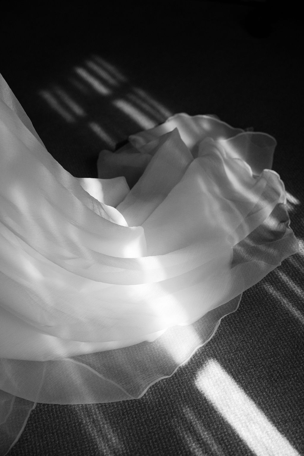 Abstract close-up of flowing white wedding dress fabric with dramatic lighting effects.