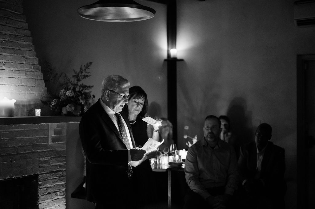 Black and white photograph of guests mingling at an evening event with dramatic lighting.