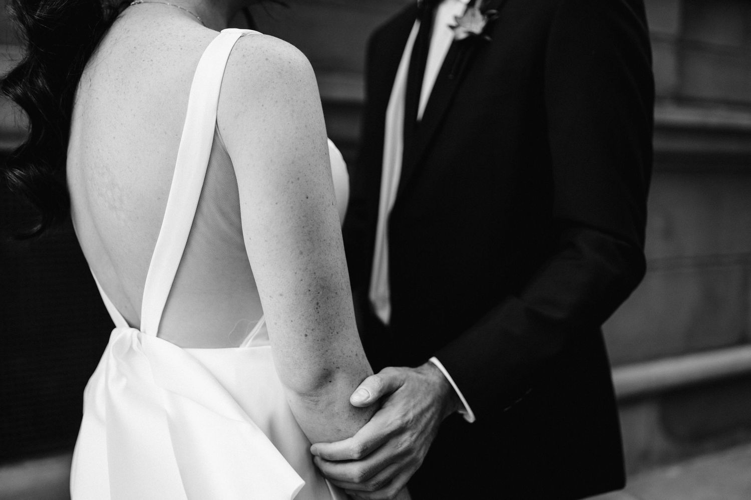Close-up detail of a bride's elegant white dress with open back design.