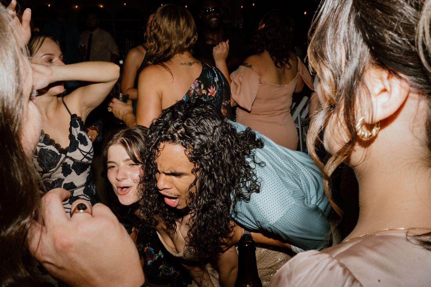 Energetic dancers enjoying a lively party on a dark dance floor with dramatic lighting.